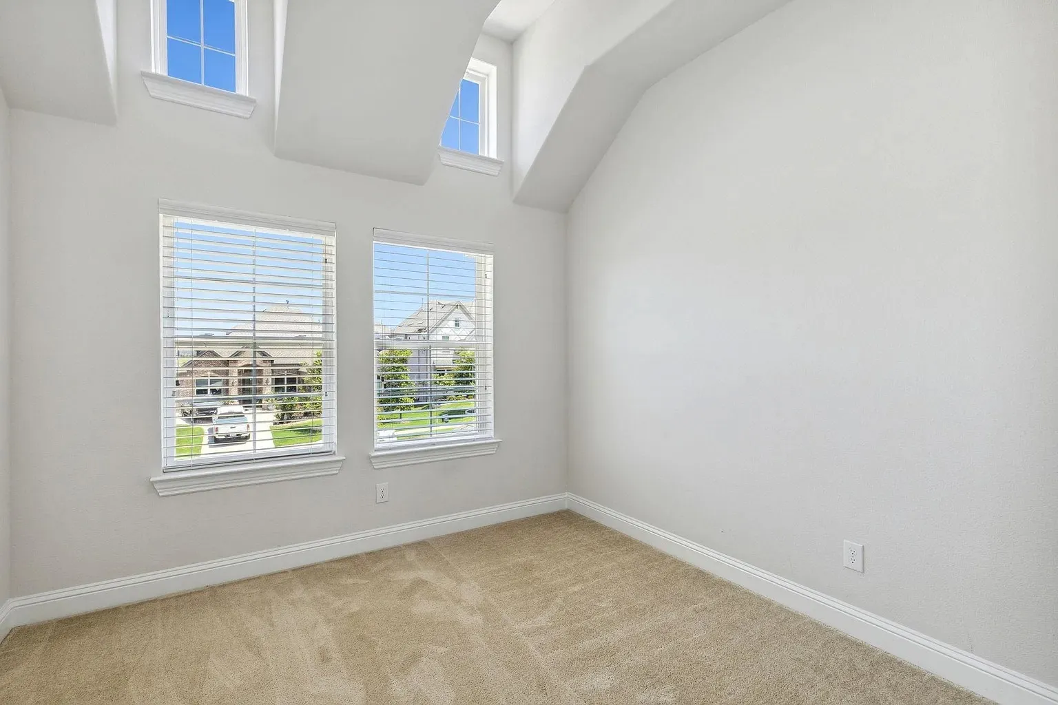 Room featuring a vaulted ceiling and four windows, including two upper-level transom windows