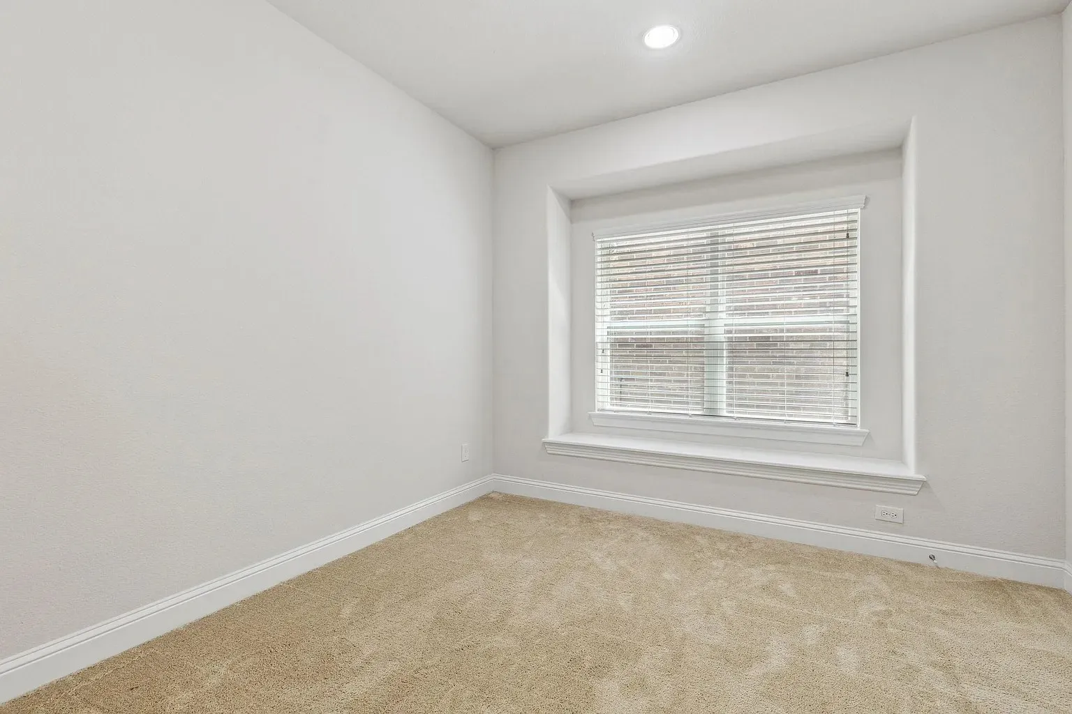Recessed window with white blinds, neutral carpeting, white baseboards, and a single recessed ceiling light fixture