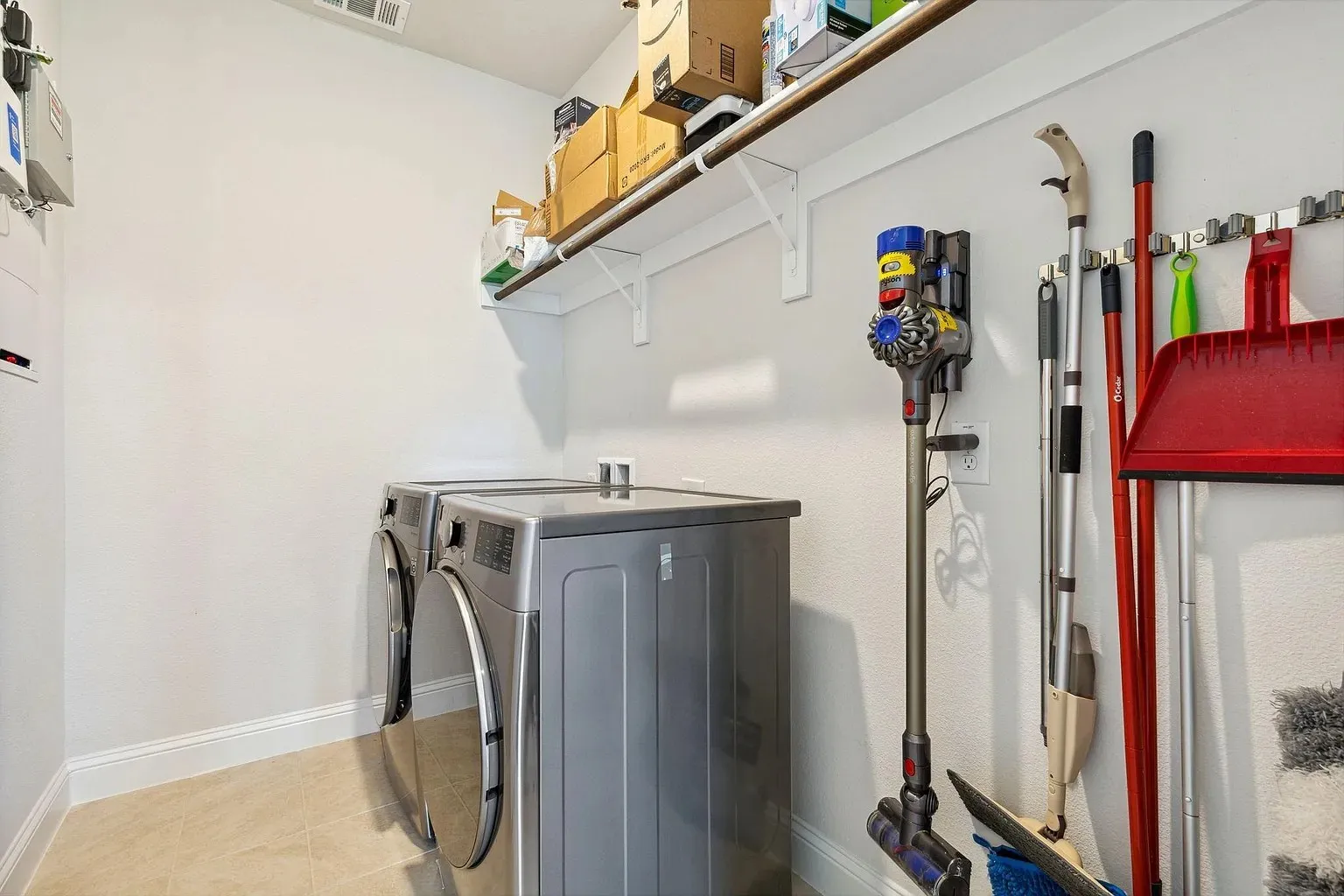 Dedicated utility space featuring a wall-mounted shelving unit, light neutral wall paint, and tiled flooring
