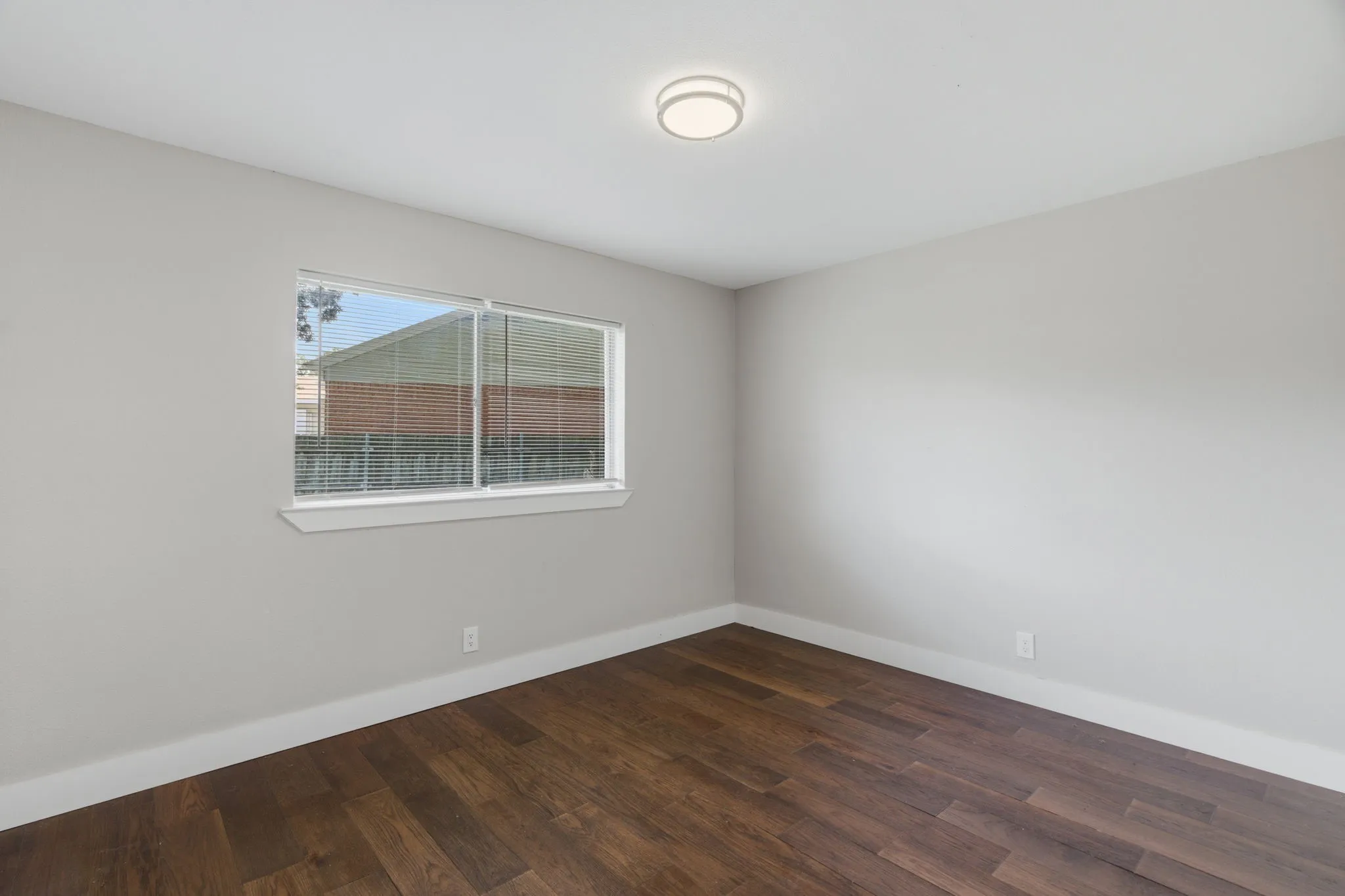 Bright room featuring wood-finish flooring, light gray wall paint, and white baseboards