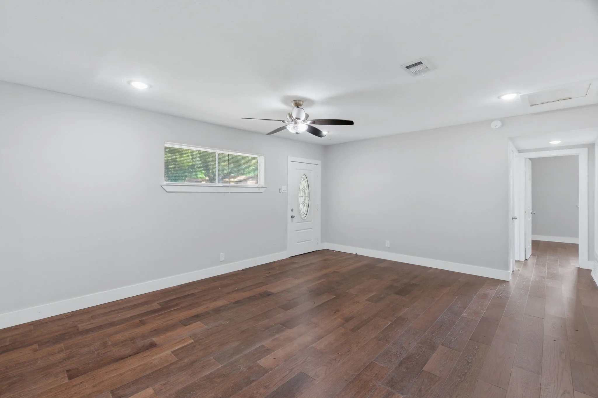 Living area featuring wood-finish flooring, light gray walls, white trim, recessed lighting, and a ceiling fan