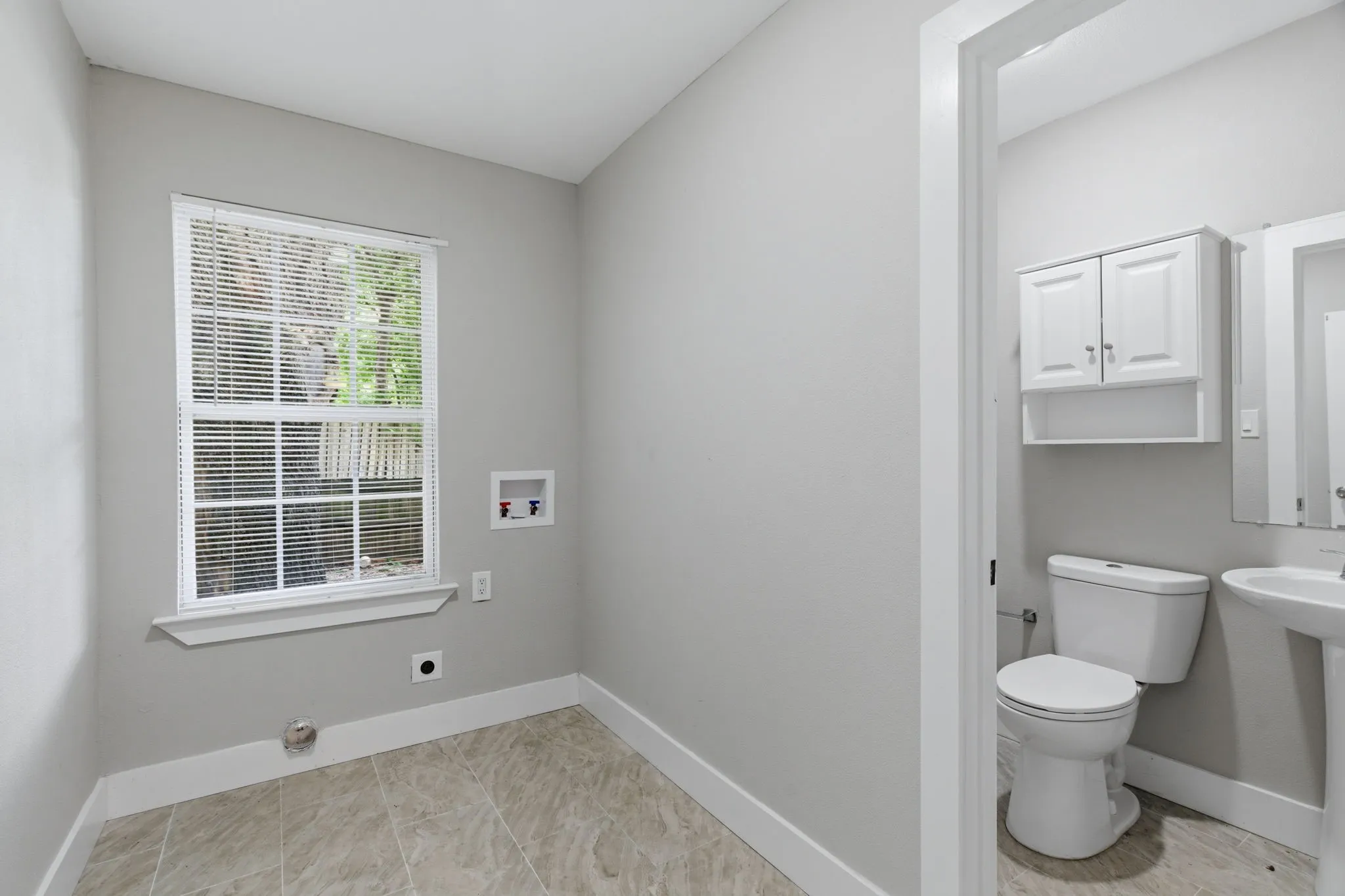Laundry area featuring tiled flooring and a window with blinds