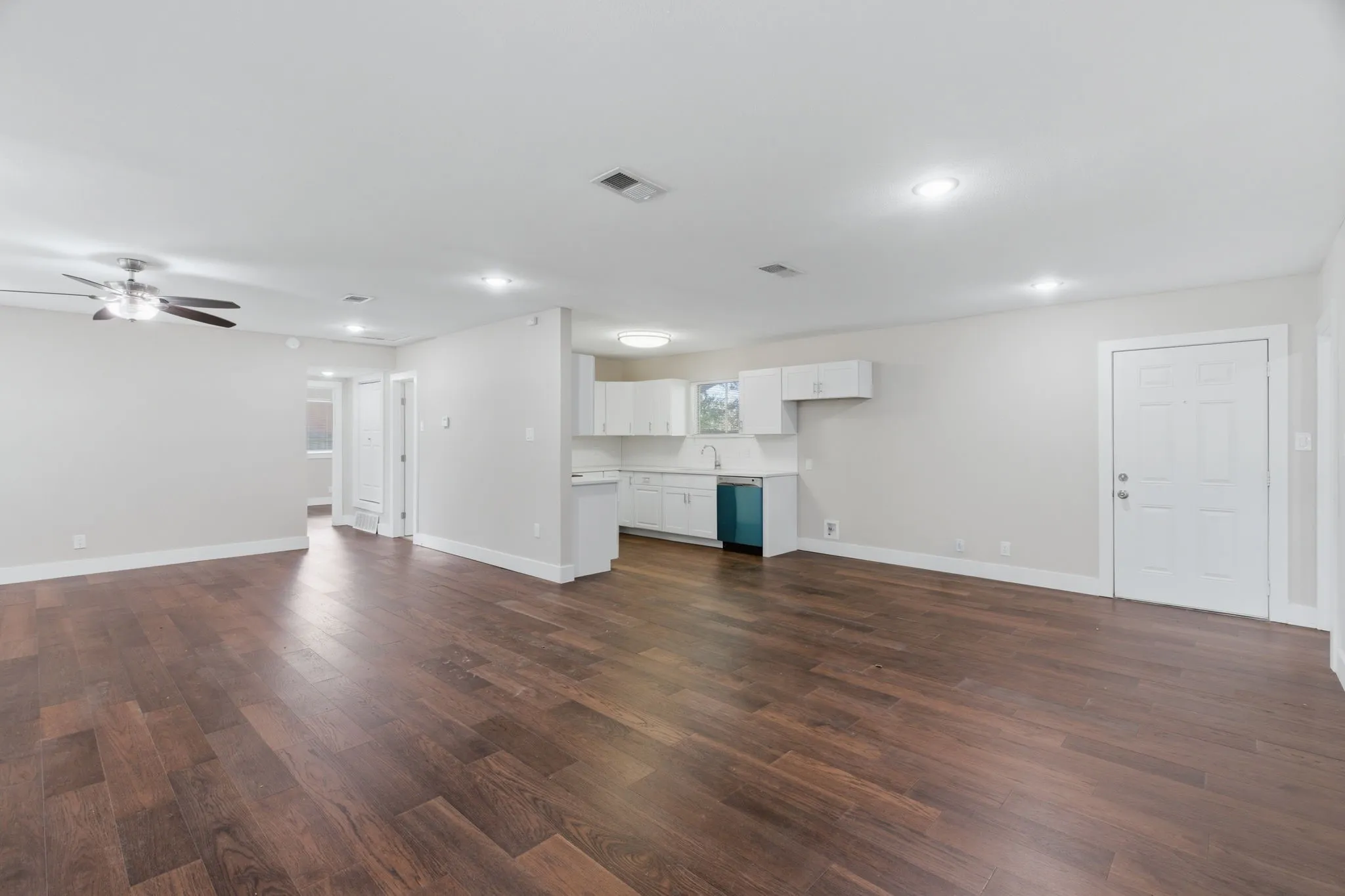 Spacious open-concept living area featuring wood-finish flooring, recessed lighting, and a ceiling fan