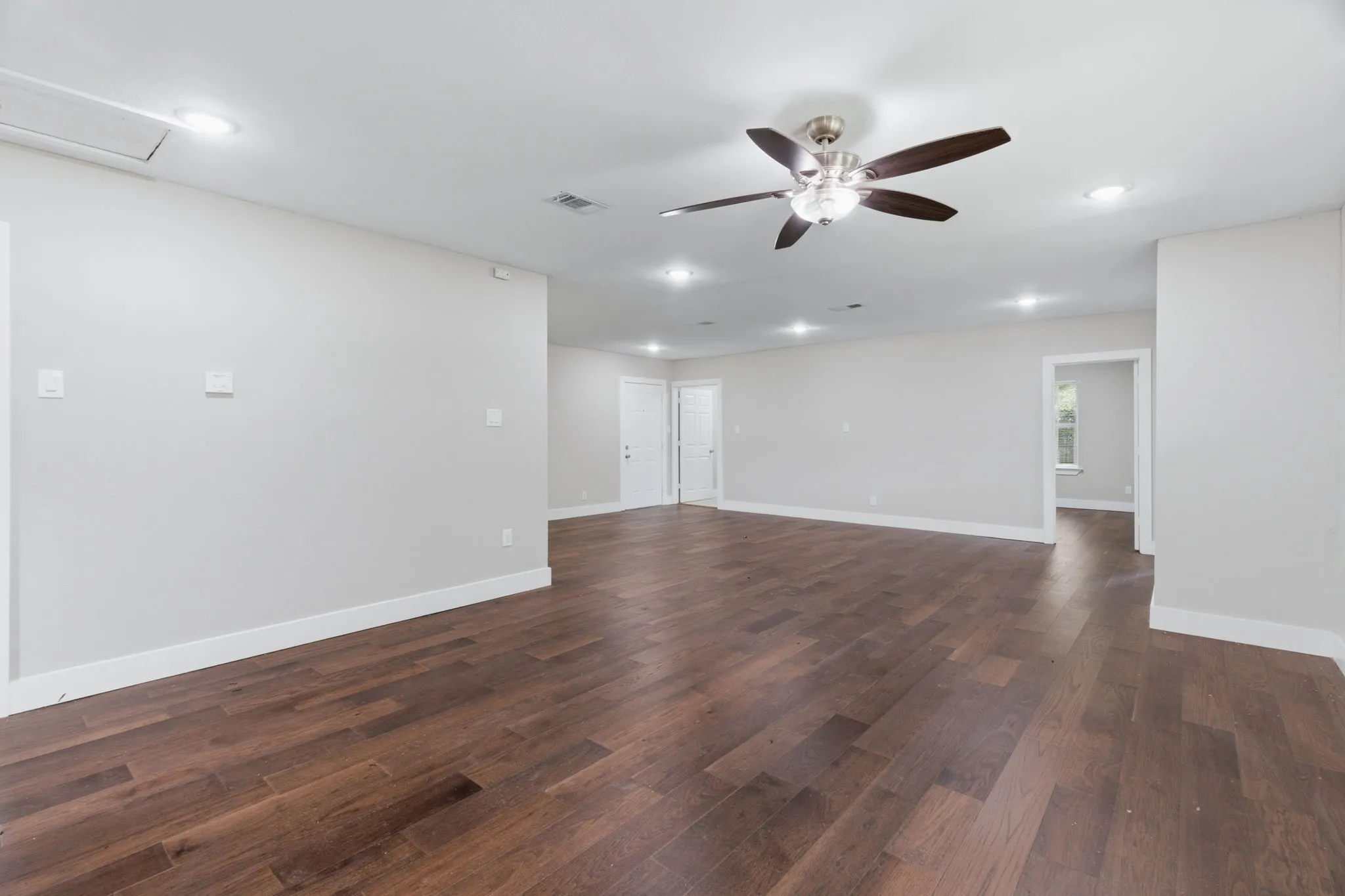 Spacious interior featuring wood-finish flooring, recessed lighting, a ceiling fan, white baseboards, and neutral wall tones