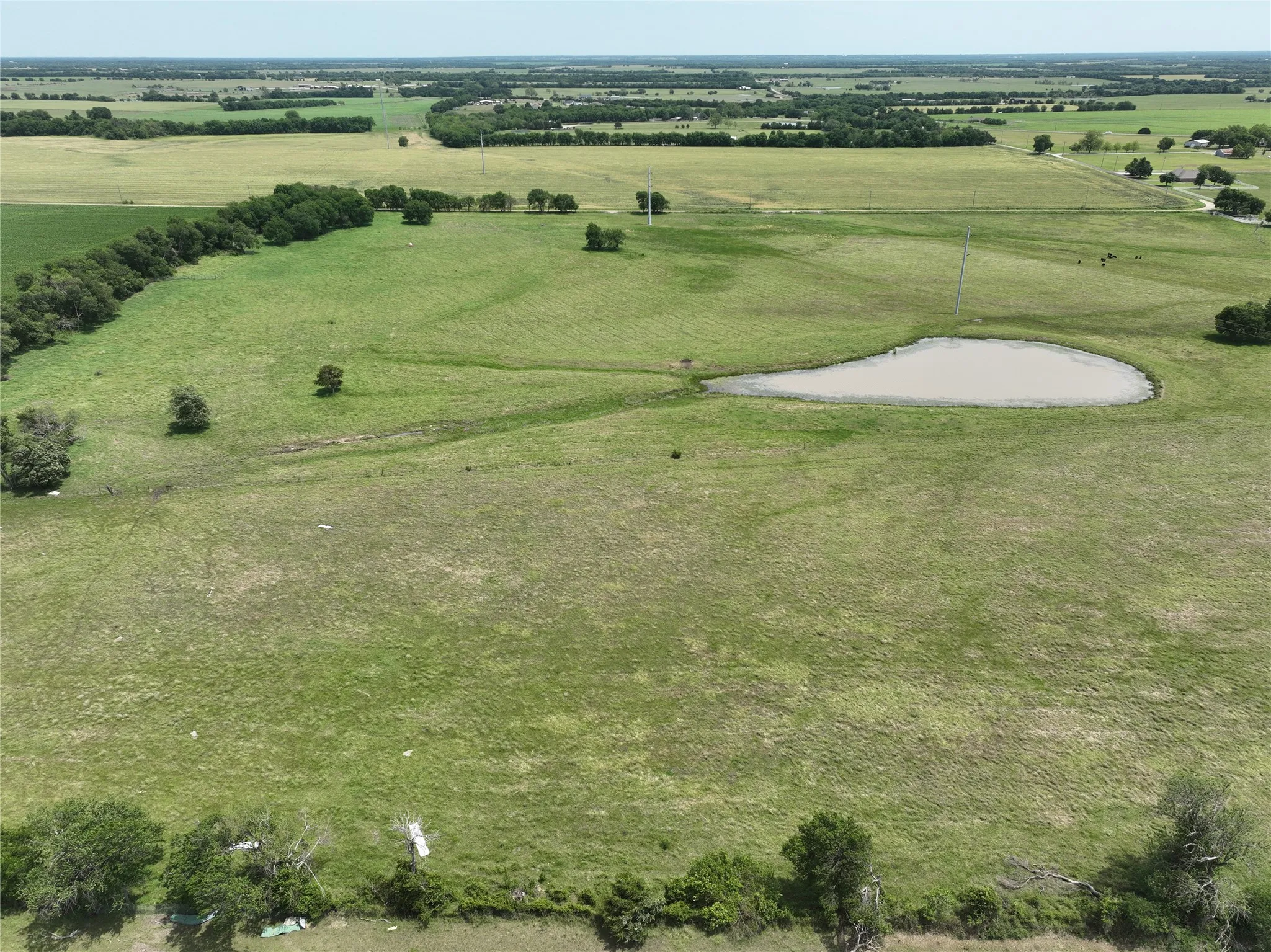 Expansive rural land featuring a natural pond, mature tree lines, and clear pastures