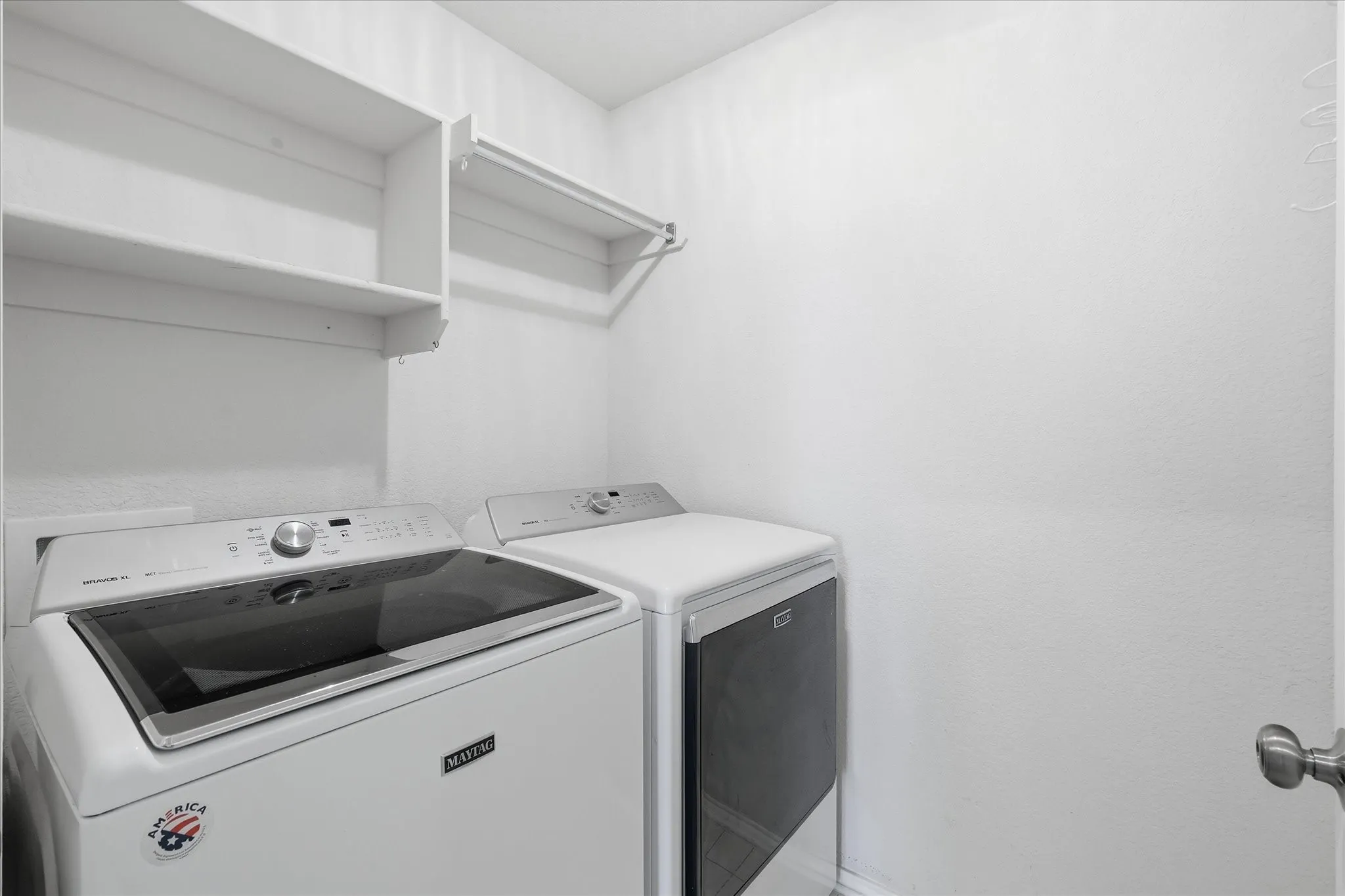 Dedicated laundry area featuring white walls, open shelving, and a built-in hanging rod