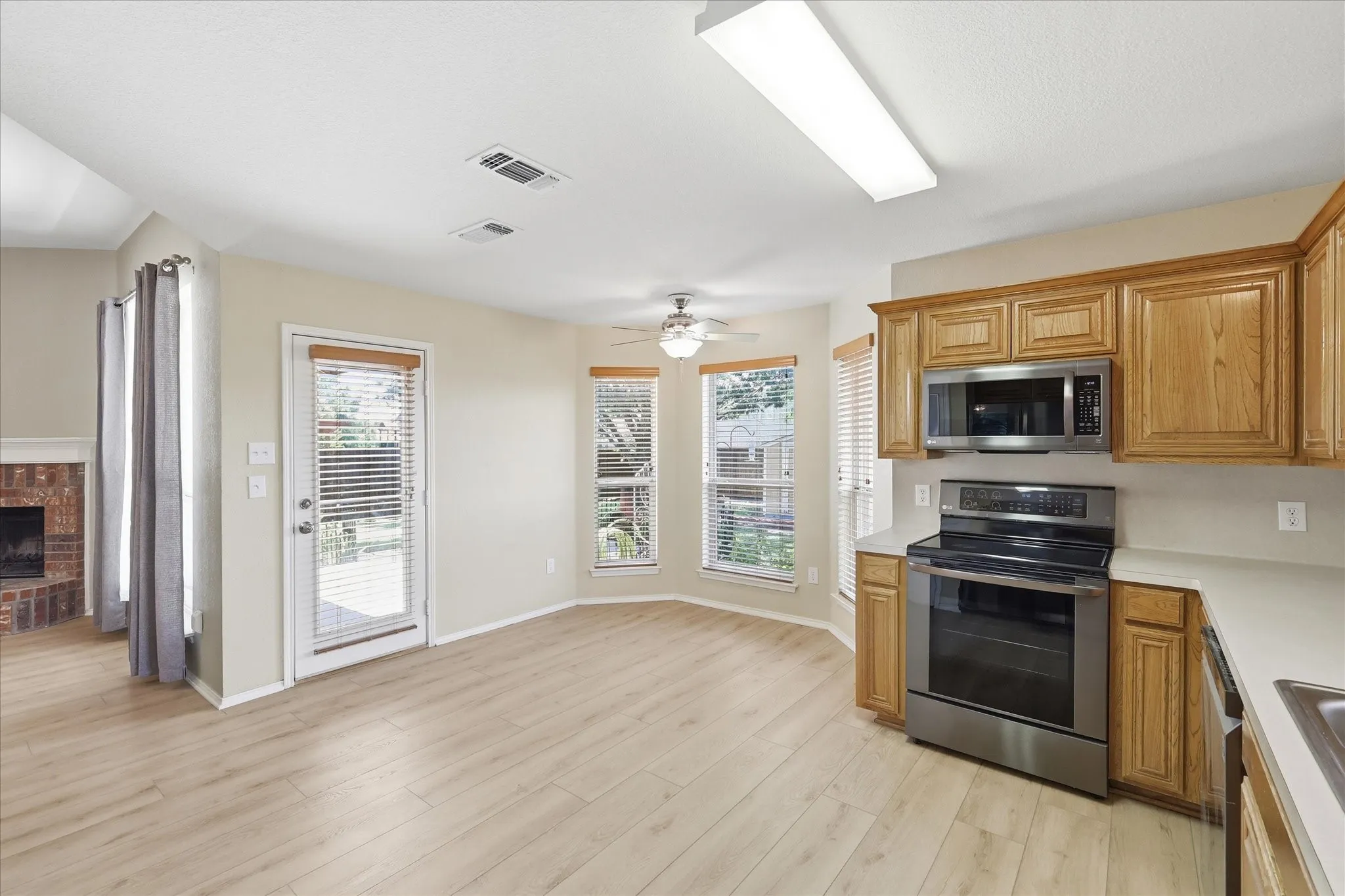 Kitchen area featuring wood-finish flooring, stainless steel appliances, wood cabinetry, and a ceiling fan