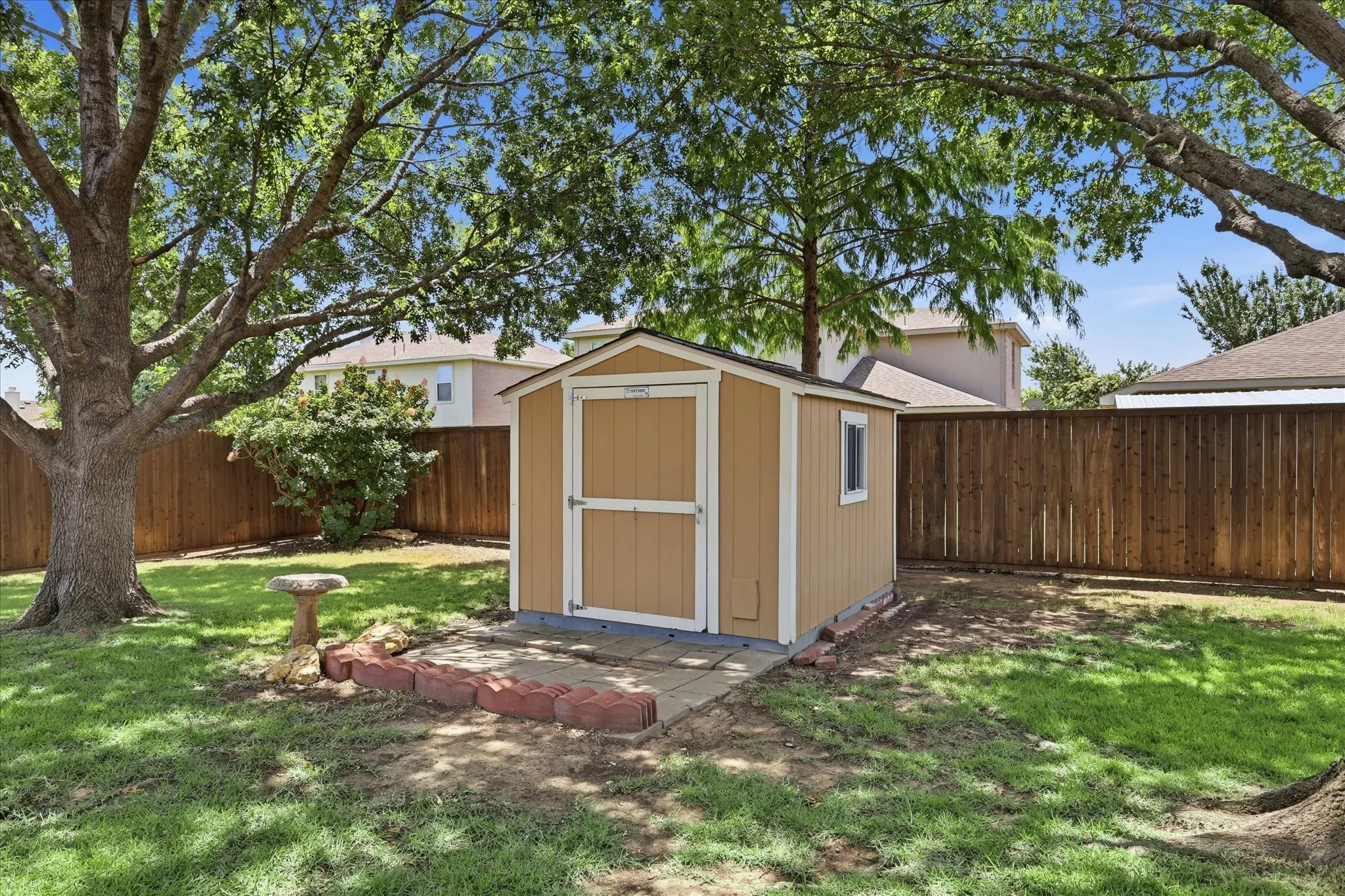 Backyard storage shed with a panel door, single window, and a concrete pad foundation