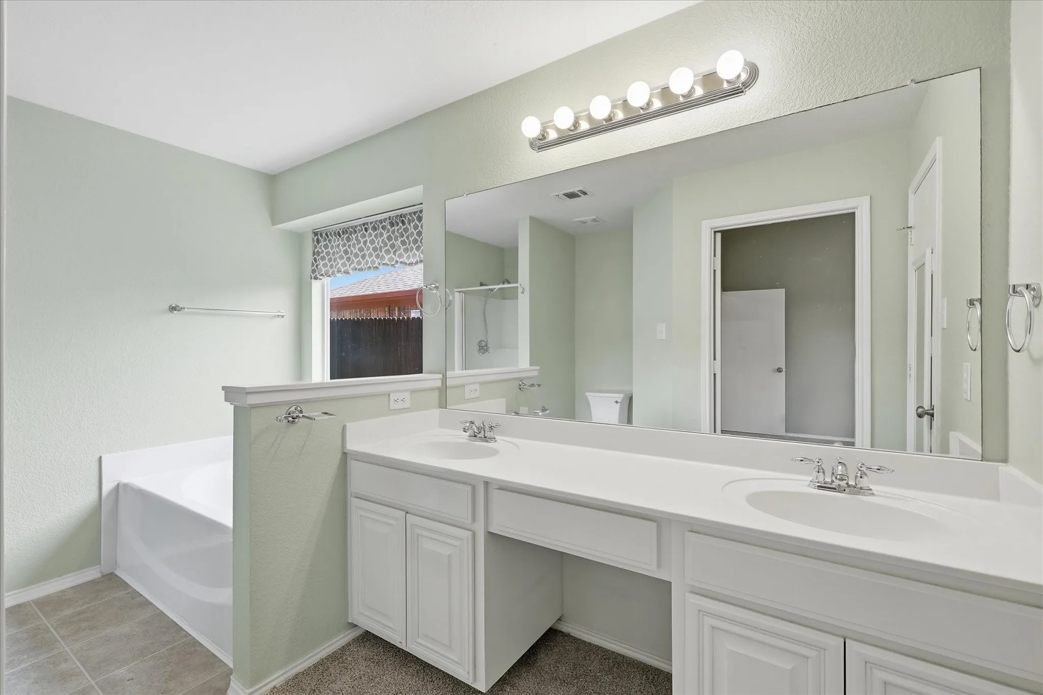 Double vanity with white cabinetry, integrated sinks, and polished chrome faucets