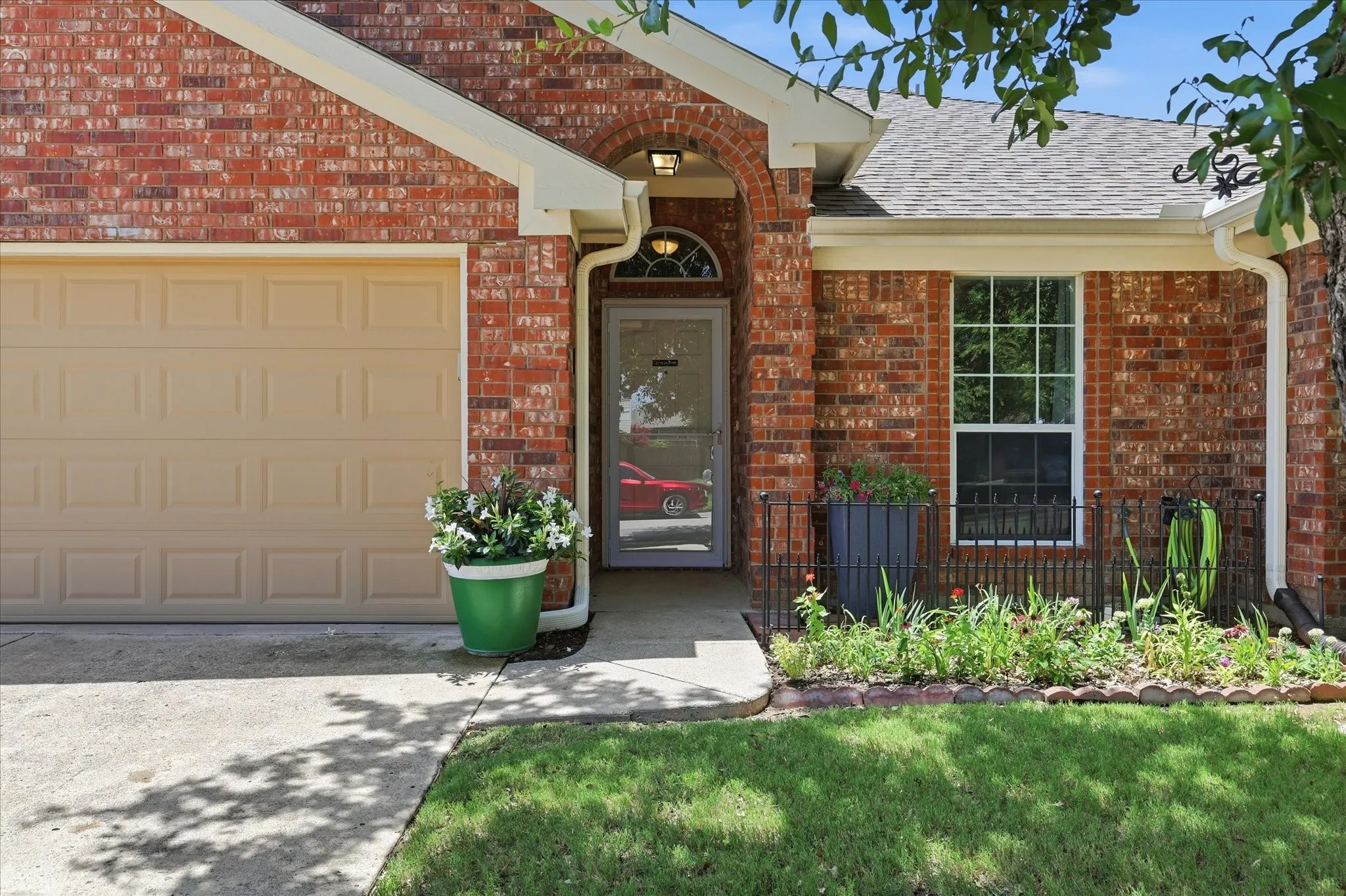 Brick exterior featuring an arched entry, a beige panel garage door, and a front window with grid pattern