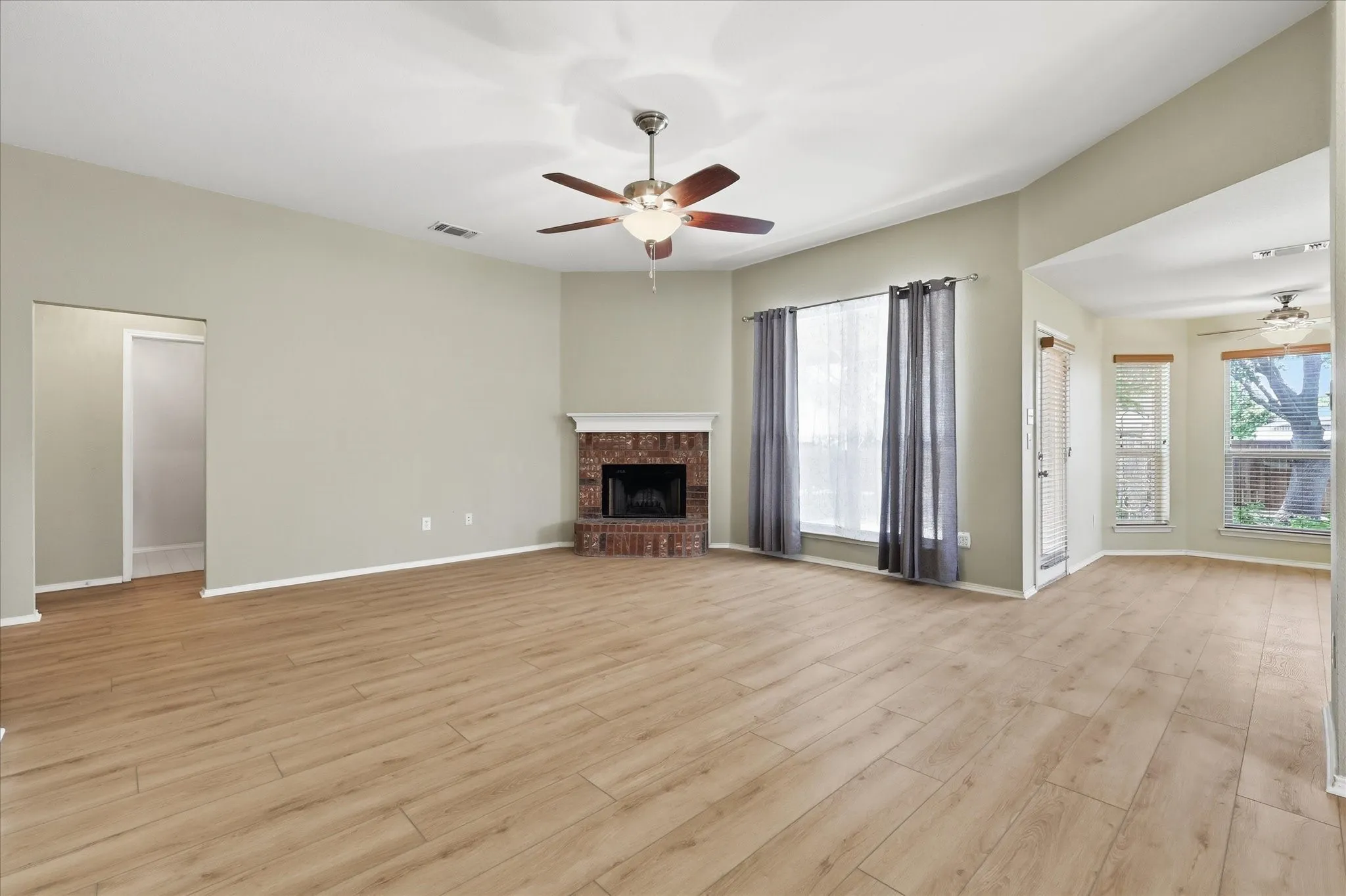 Spacious living area featuring wood-finish flooring and a brick fireplace
