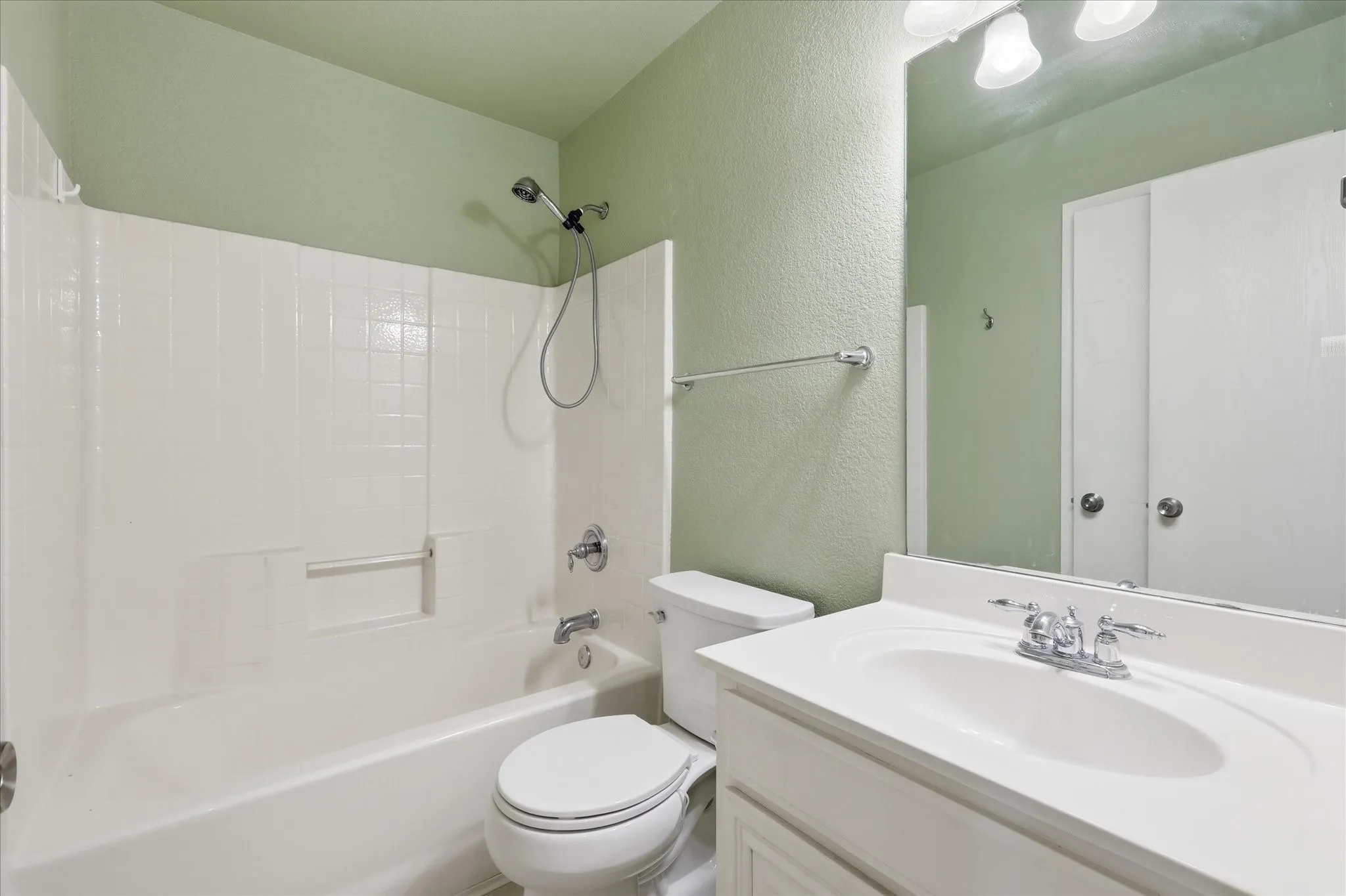 Bathroom featuring a white vanity with integrated sink, chrome faucet, and overhead vanity lighting