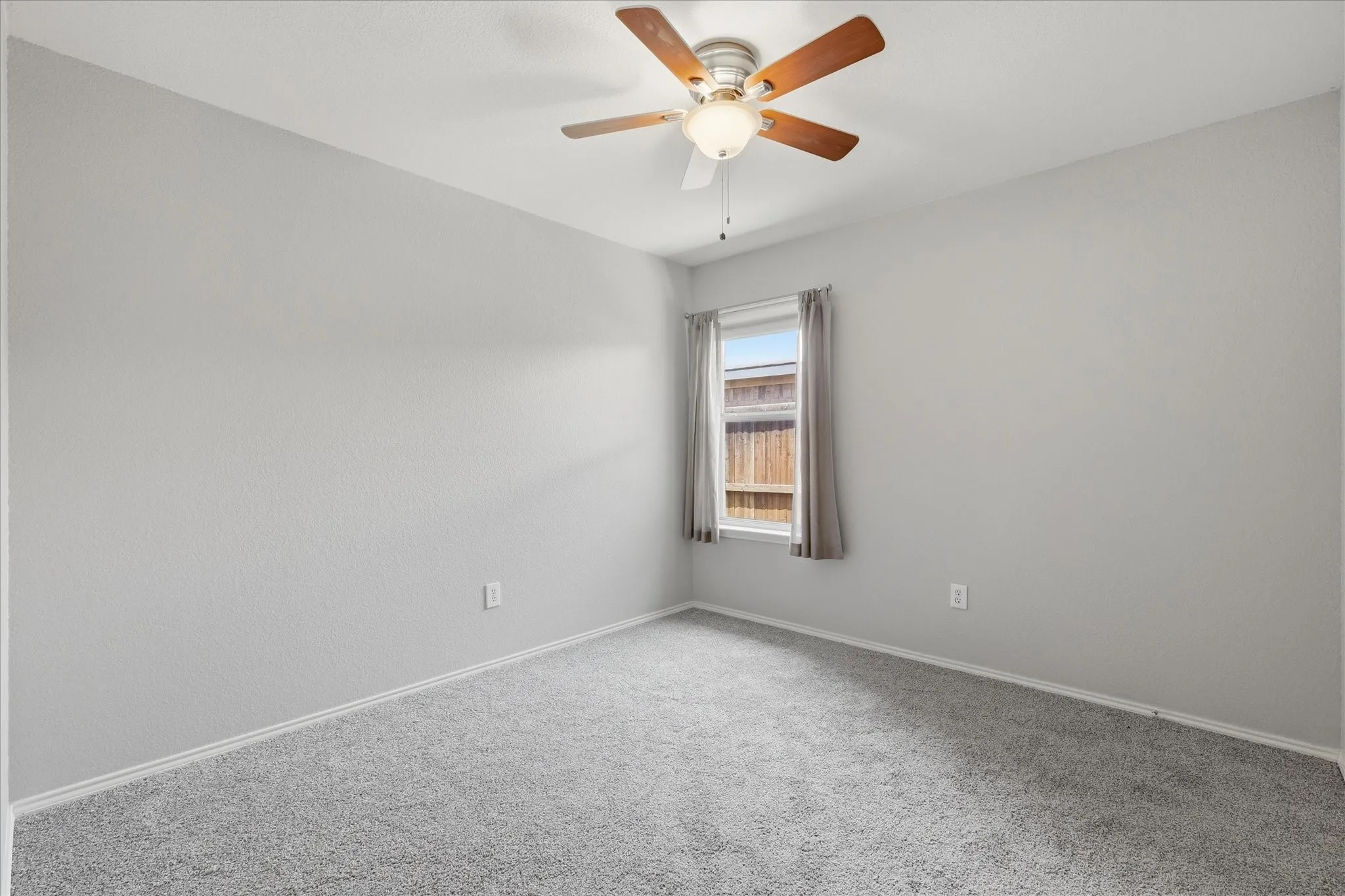 Bedroom featuring grey carpeting, light grey walls, a single window with blinds and drapes, and a ceiling fan with light