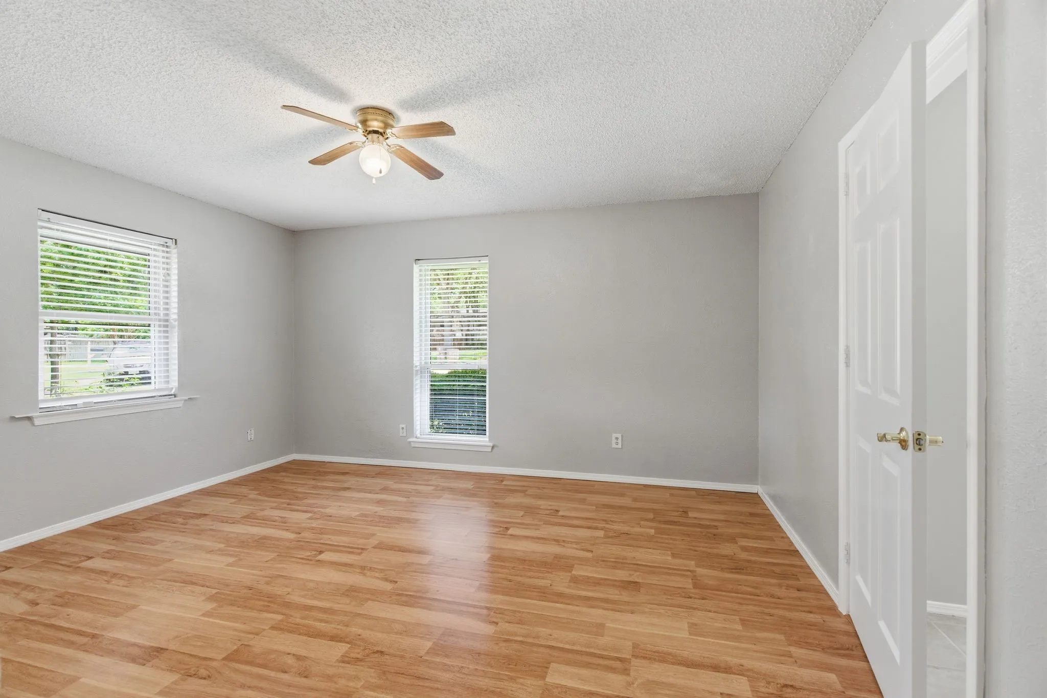 Spacious primary retreat with natural light and warm wood-look flooring