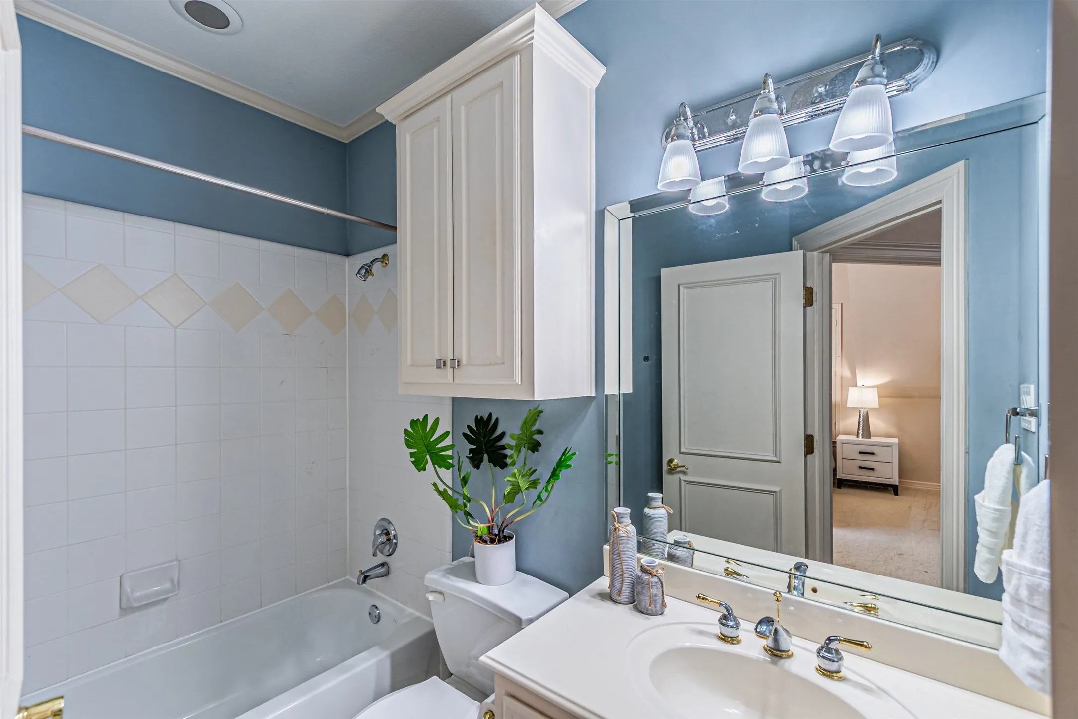 Bathroom vanity with an integrated sink, polished brass and chrome fixtures, and a large mirrored wall