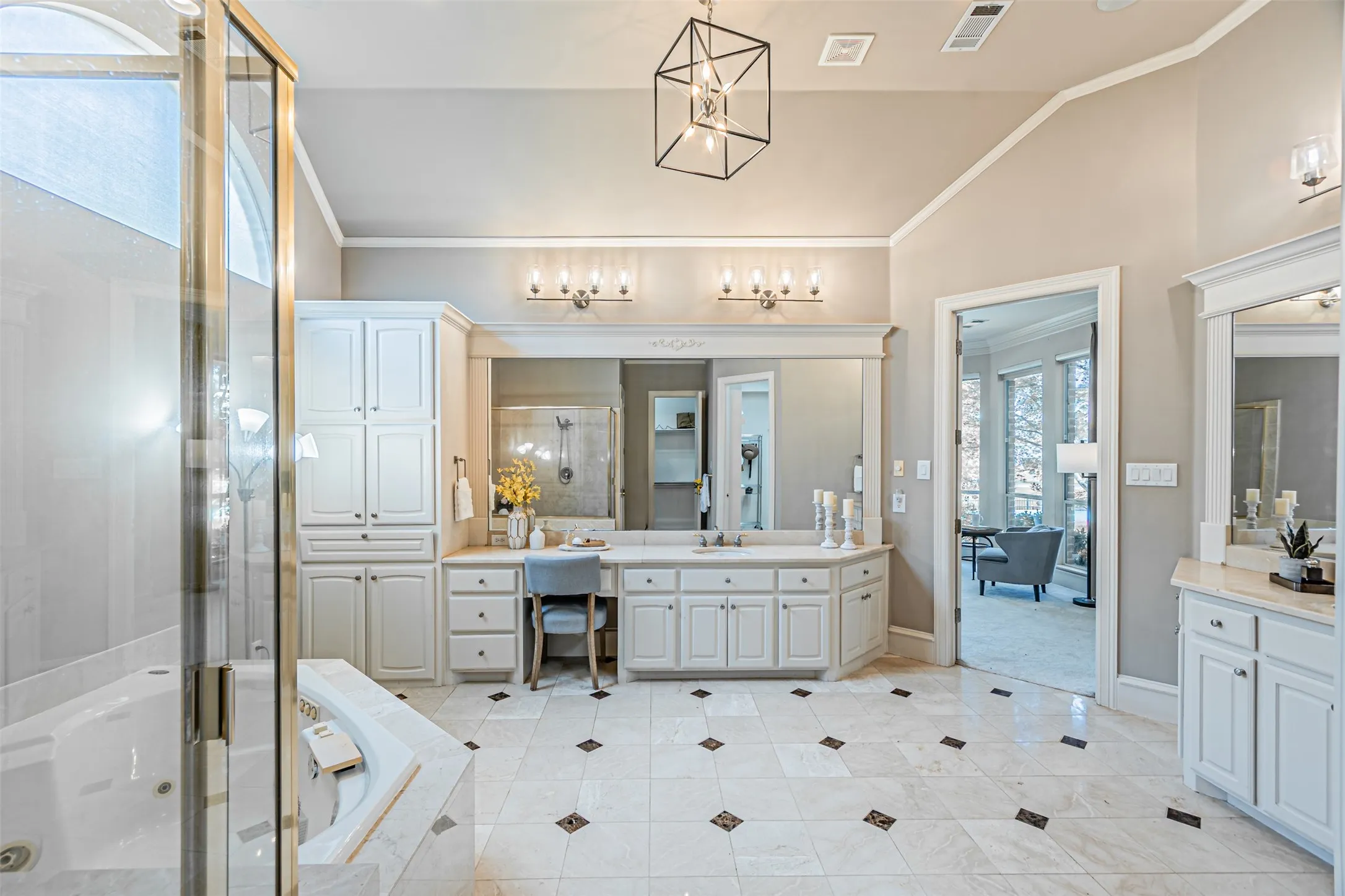 Spacious bathroom featuring a white soaking tub, glass-enclosed shower, dual vanity with undermount sinks, separate make-up vanity, and light-toned tile flooring with dark accent squares