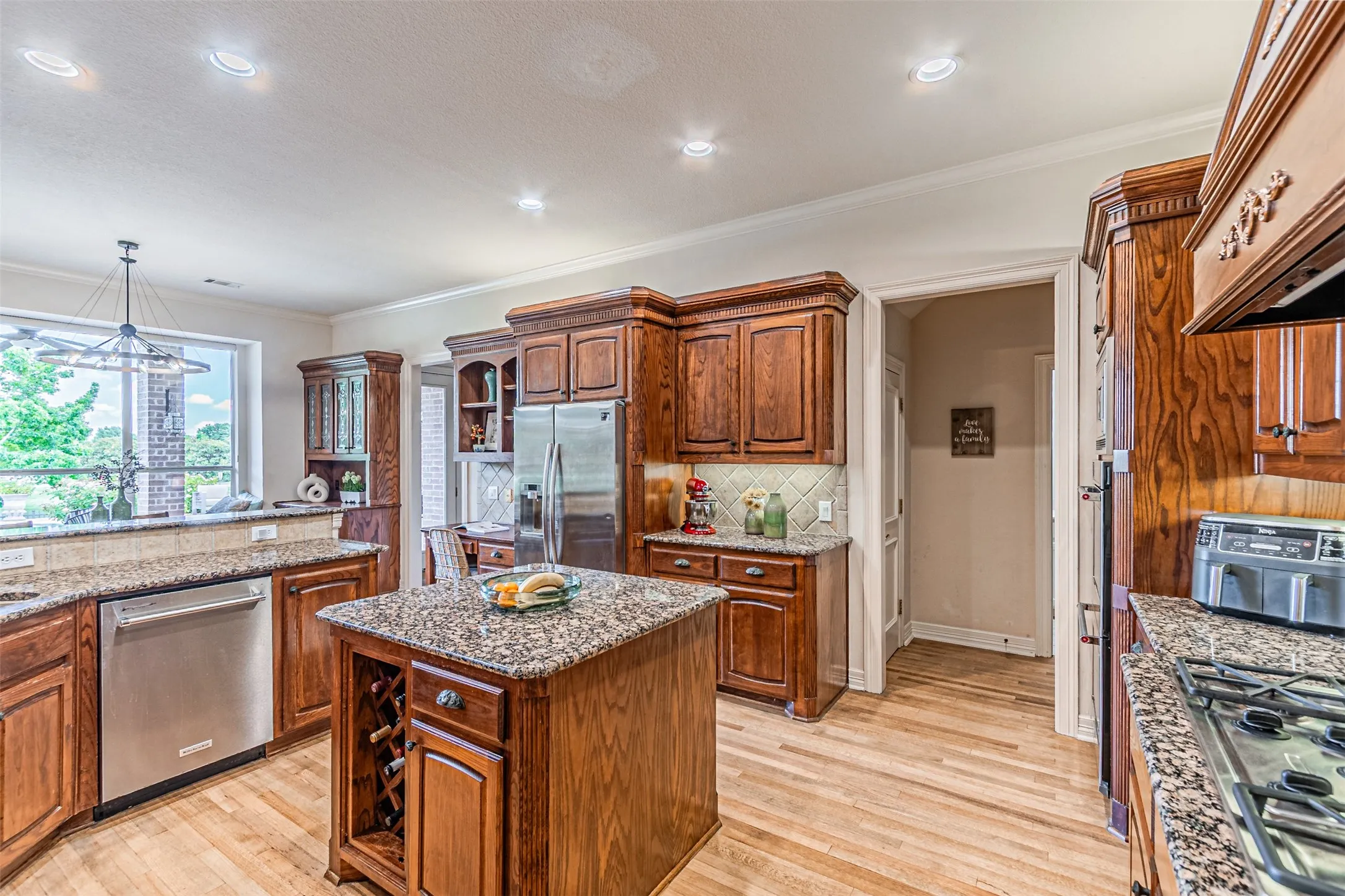 Kitchen featuring granite countertops, wood-finish flooring, recessed lighting, and a central island with a built-in wine rack