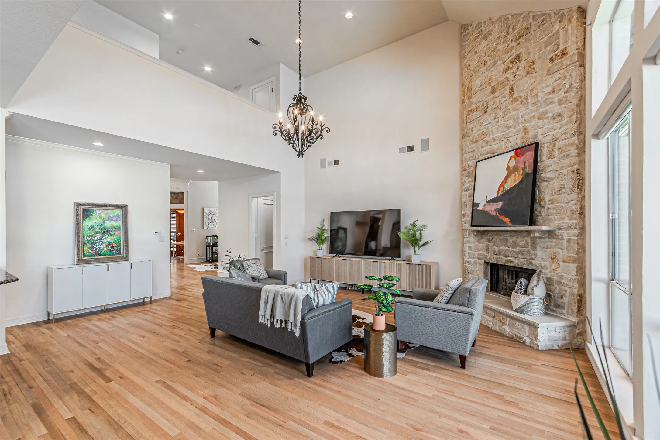 Living area with wood-finish flooring, a vaulted ceiling, and a stone-clad fireplace