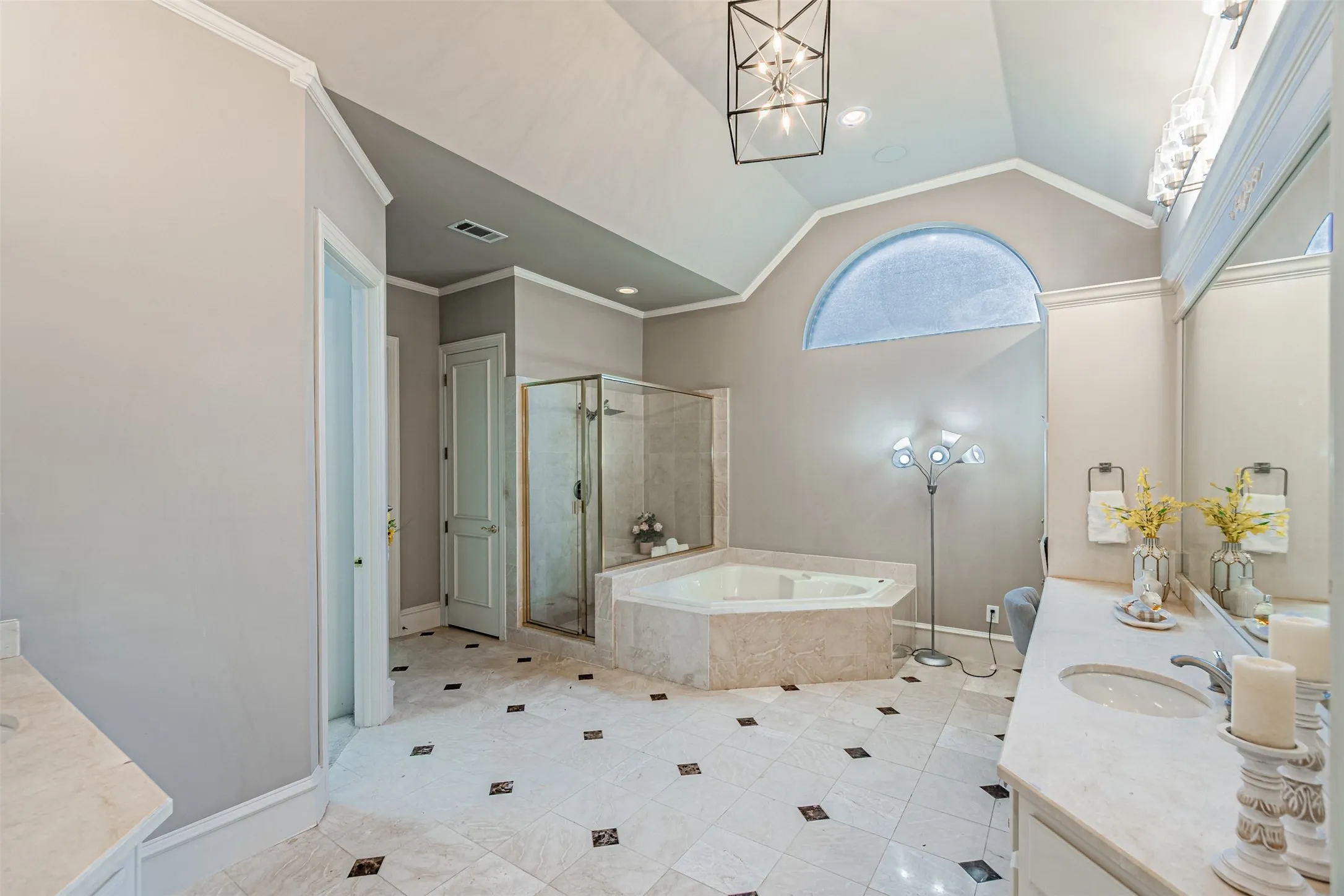Bathroom featuring a vaulted ceiling, an arched transom window, and a corner jetted tub