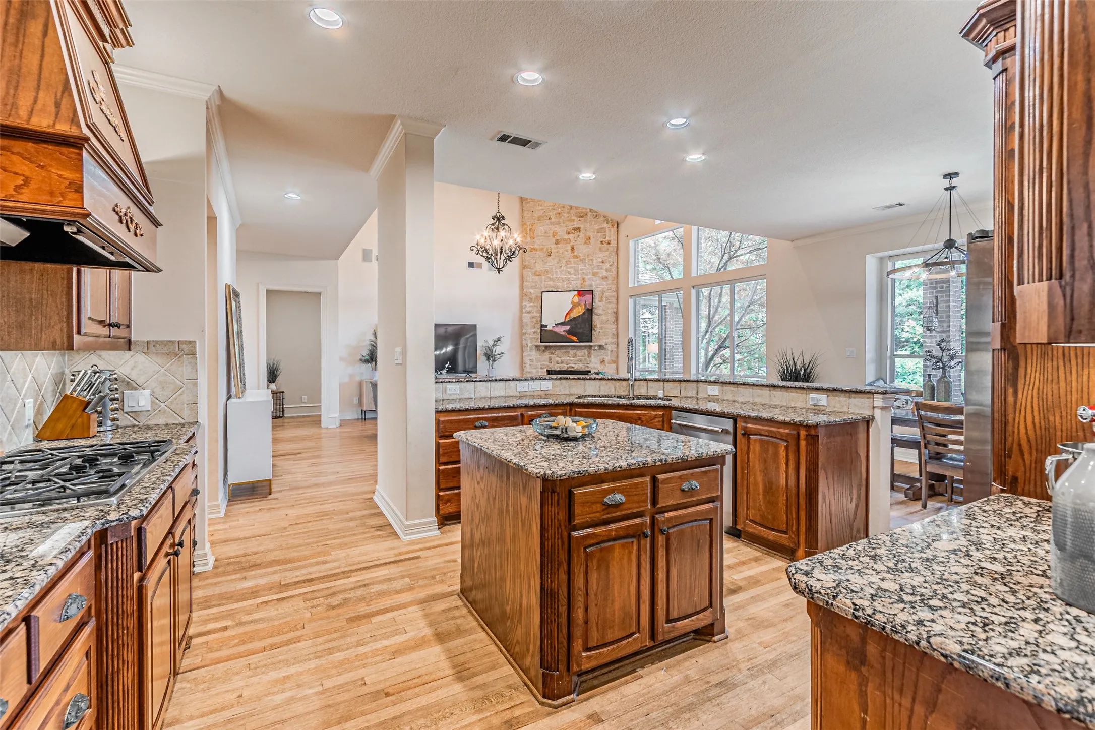 Kitchen featuring wood-finish flooring, granite countertops, wood cabinetry, a central island, and a gas range