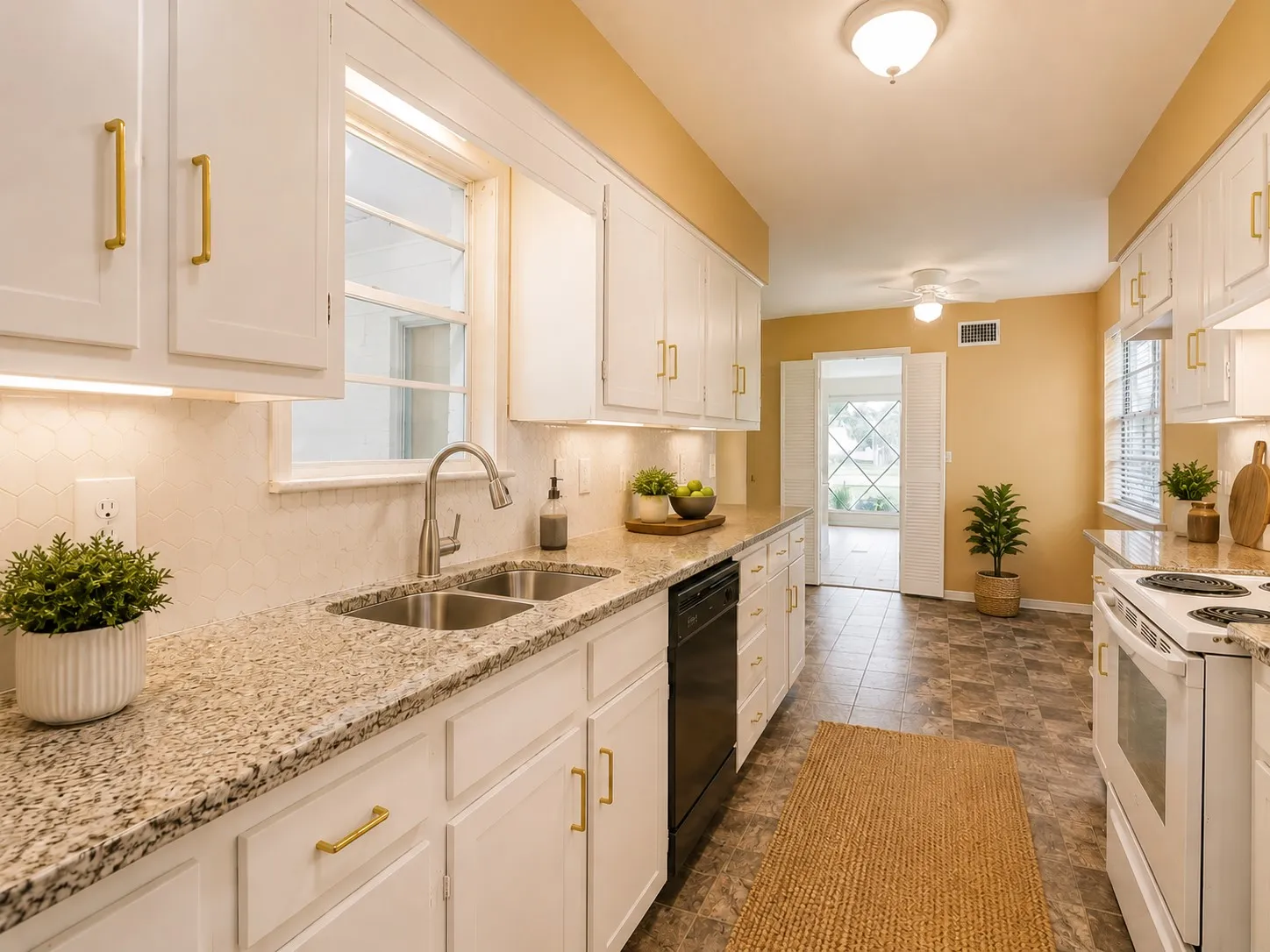 Bright kitchen featuring white cabinetry with gold-tone hardware, granite-style countertops, and a hexagonal tile backsplash