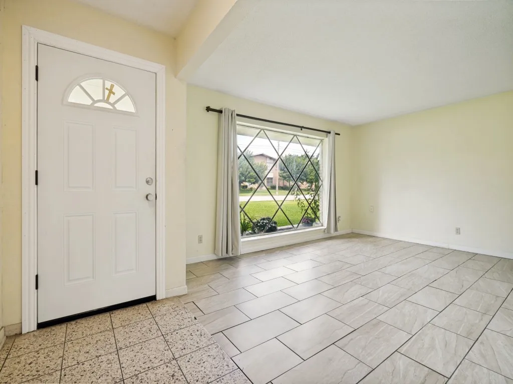 Entryway featuring a paneled door with an arched window insert and a diamond-patterned window with exterior landscaping