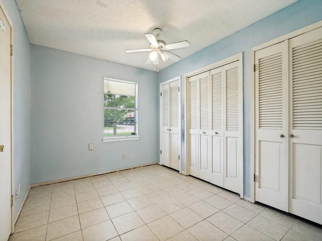 Room with tiled flooring, white louvered bifold closet doors, and a ceiling fan with light fixture