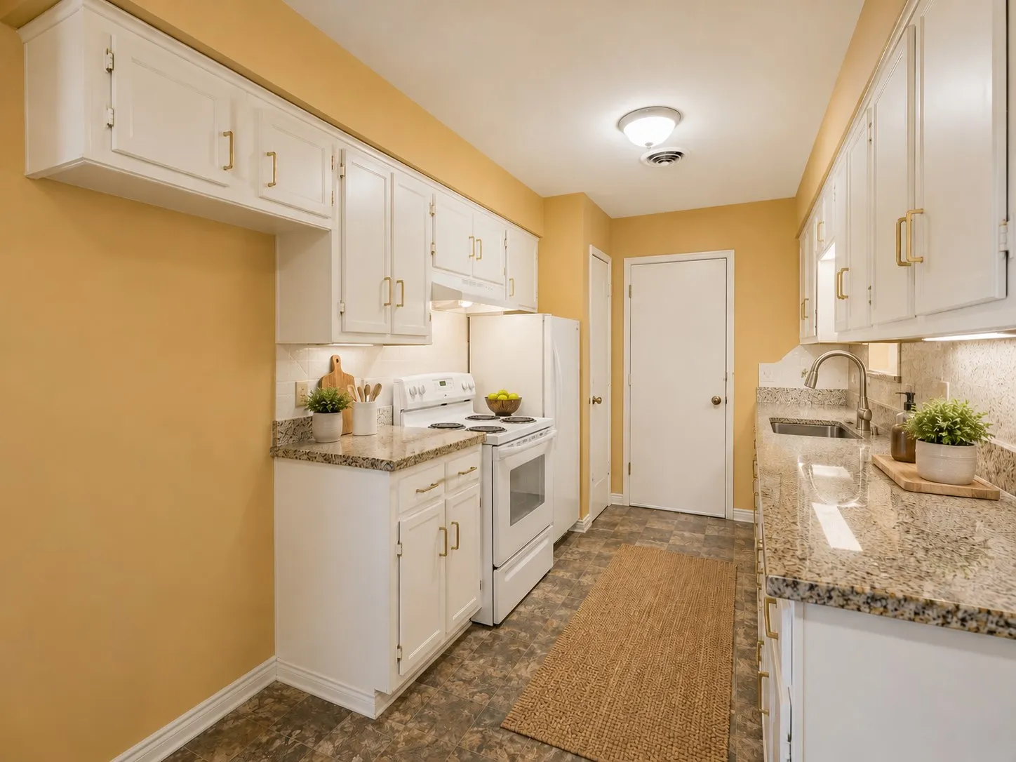 Galley kitchen featuring white cabinetry, gold-tone hardware, and granite countertops