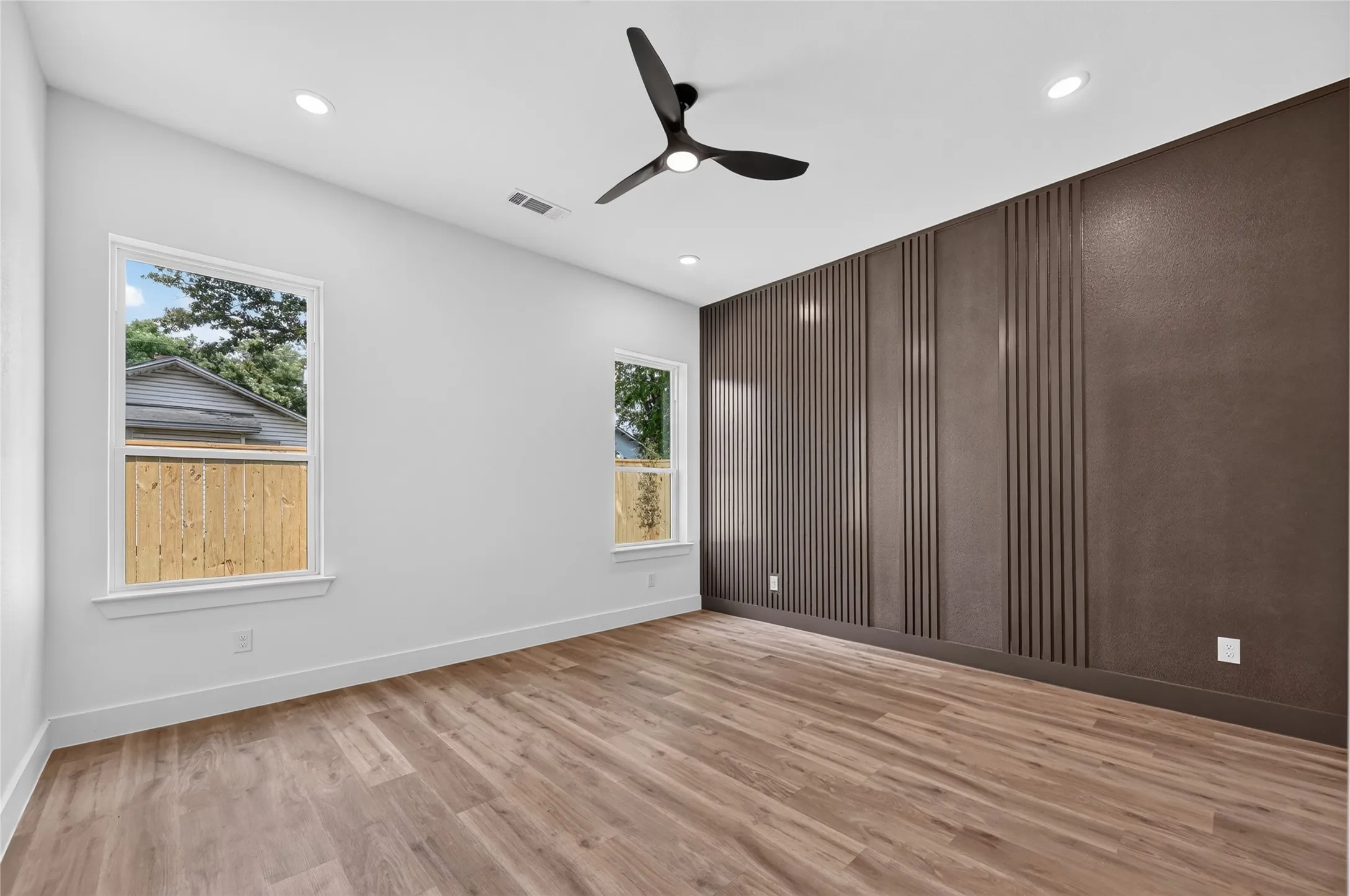 Spacious room featuring wood-finish flooring and a contemporary black ceiling fan