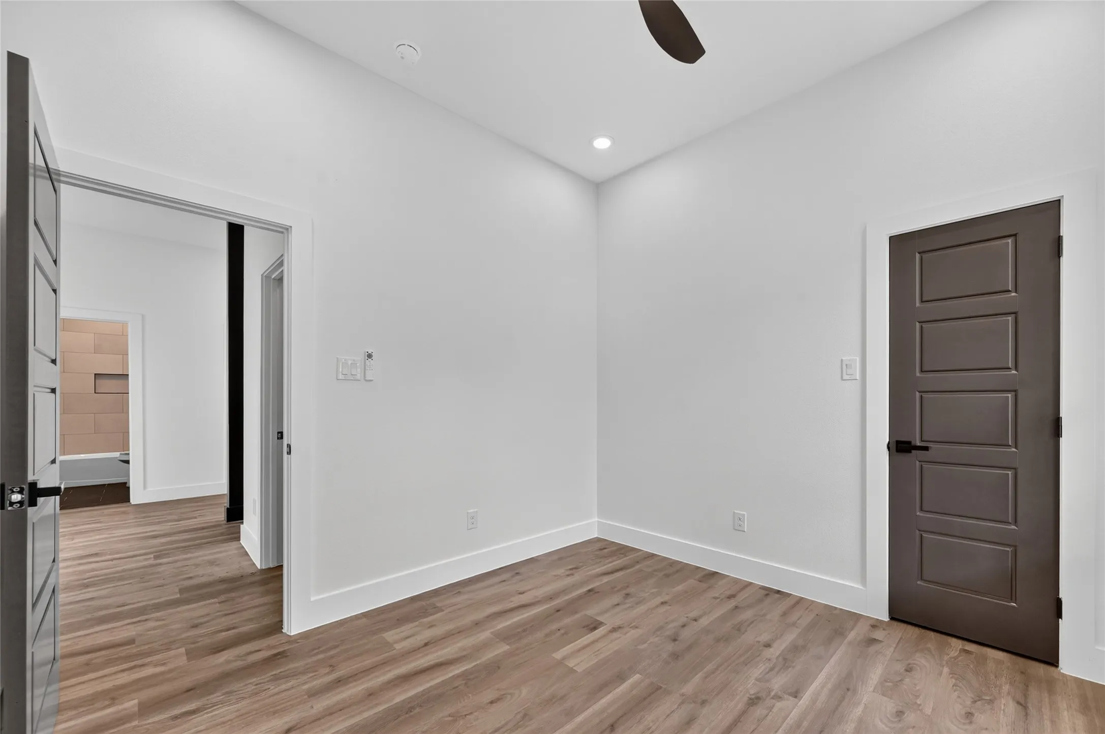 Interior room with wood-finish flooring, white walls, recessed lighting, and a ceiling fan