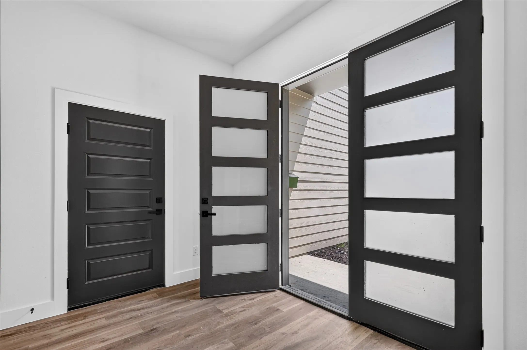 Entryway featuring a modern black door with frosted glass panels and a solid black panel door