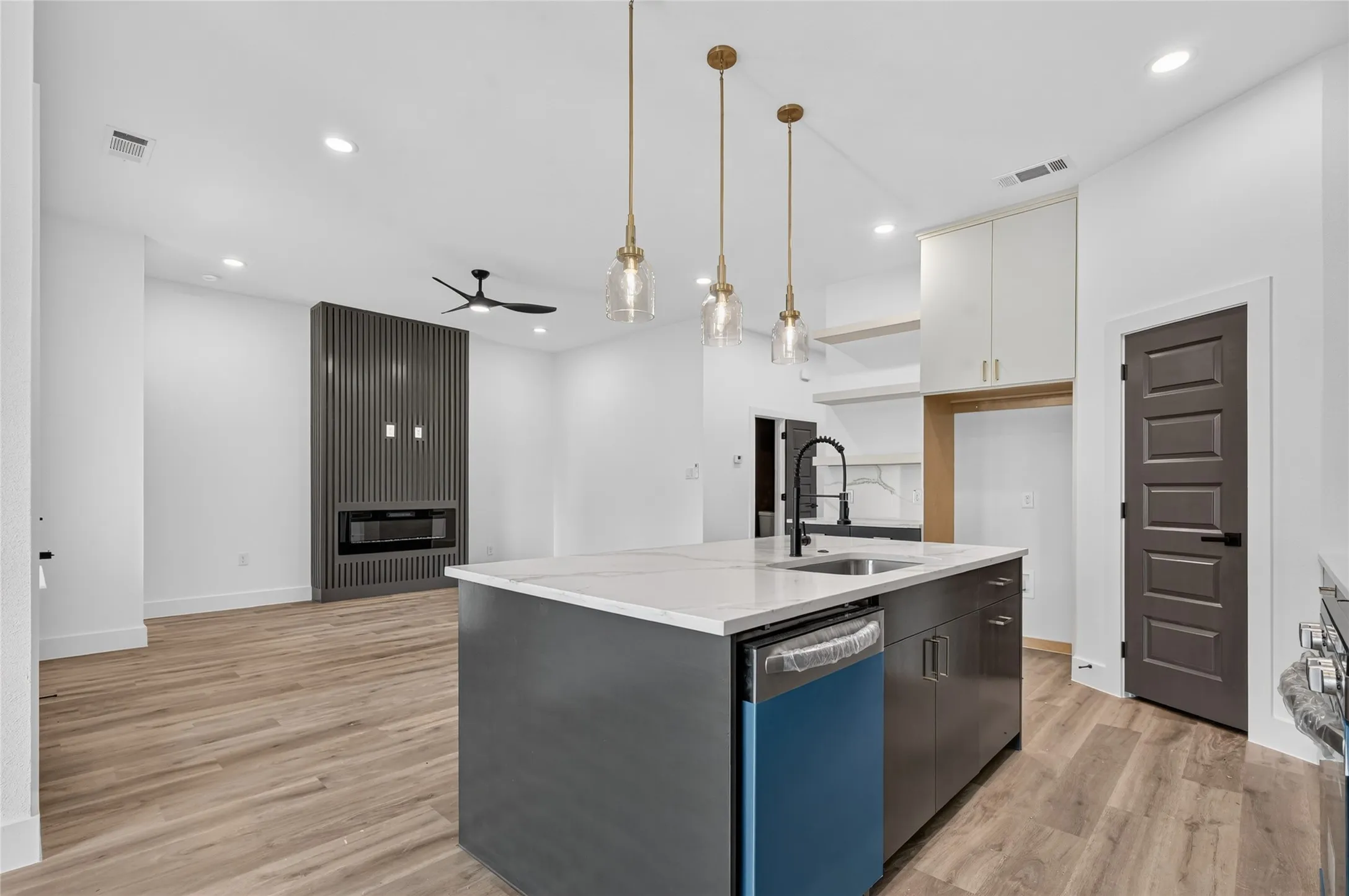 Open-concept living space featuring a kitchen island with pendant lighting, a built-in dishwasher, and a deep sink
