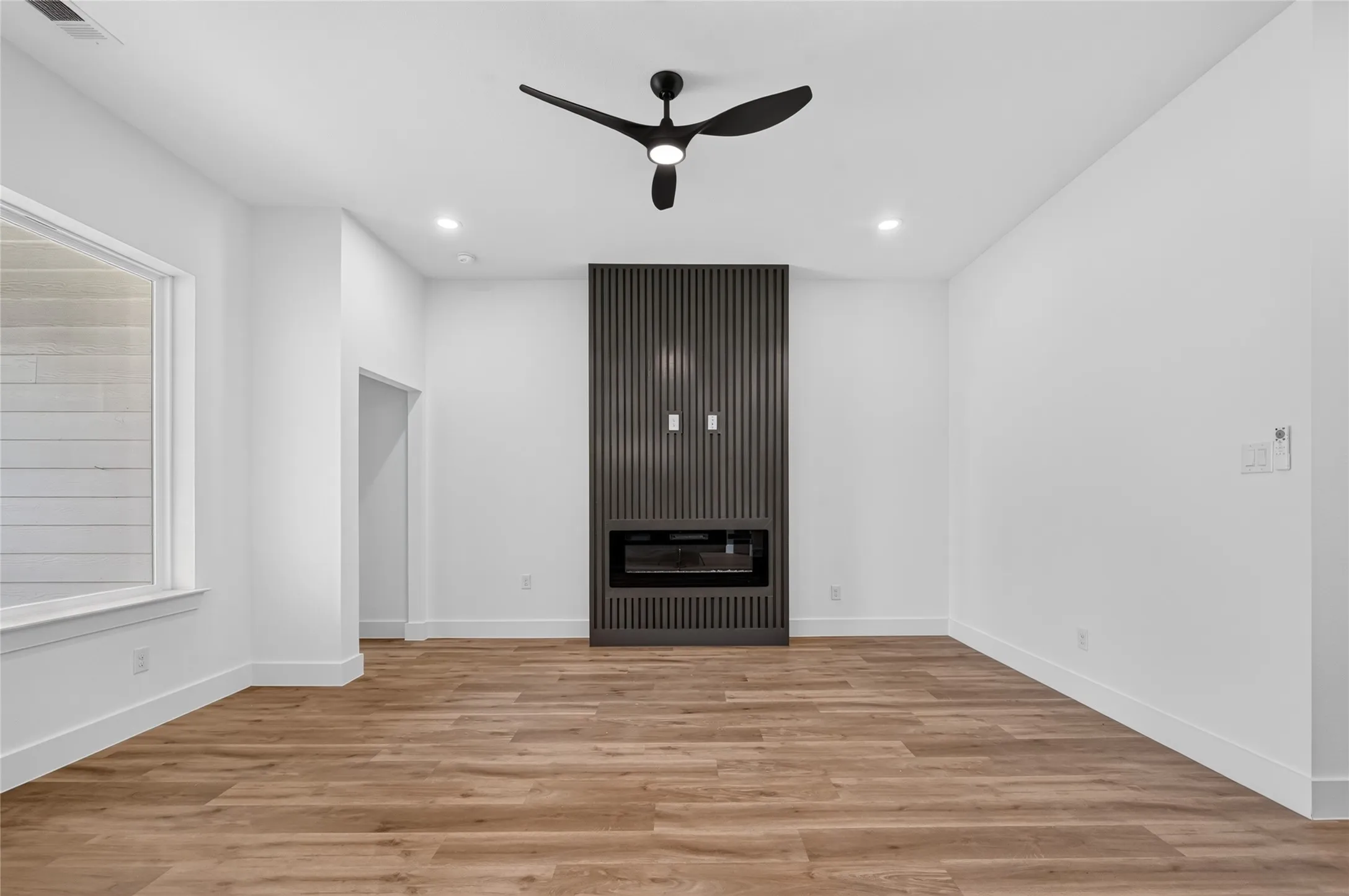 Contemporary interior featuring wood-finish flooring and an accent wall with a built-in electric fireplace