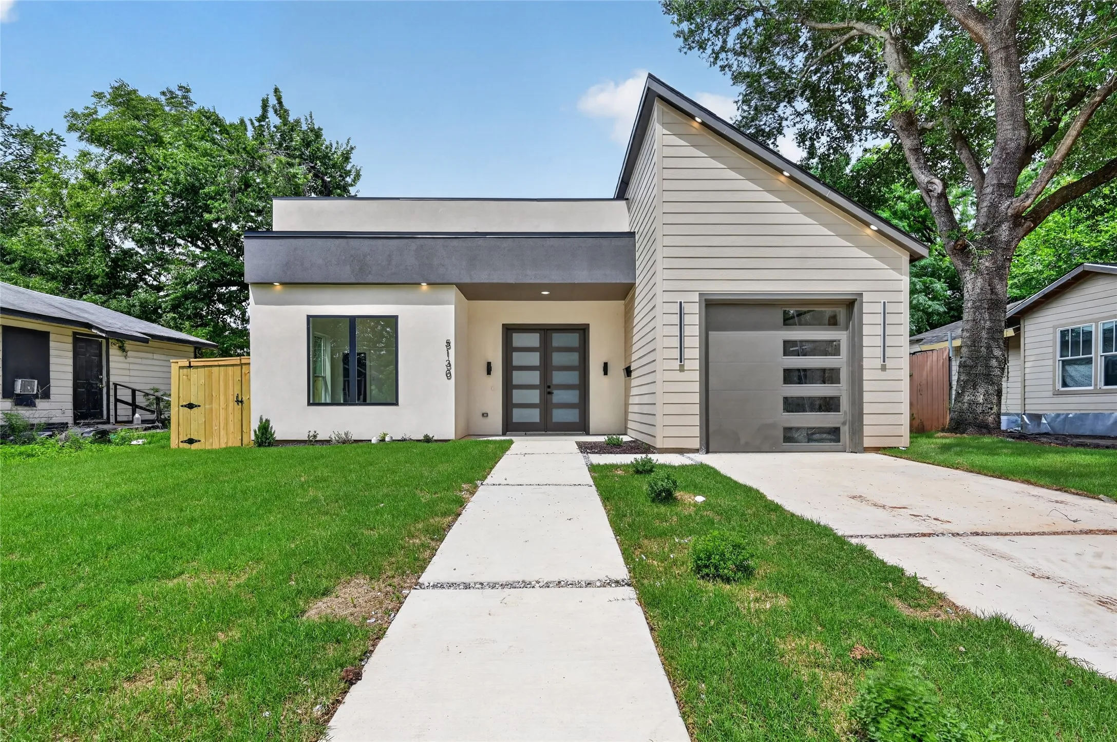Contemporary exterior featuring a flat roofline and a sharply angled gable roof, a modern garage door with rectangular window inserts, and a dual-panel glass entry door