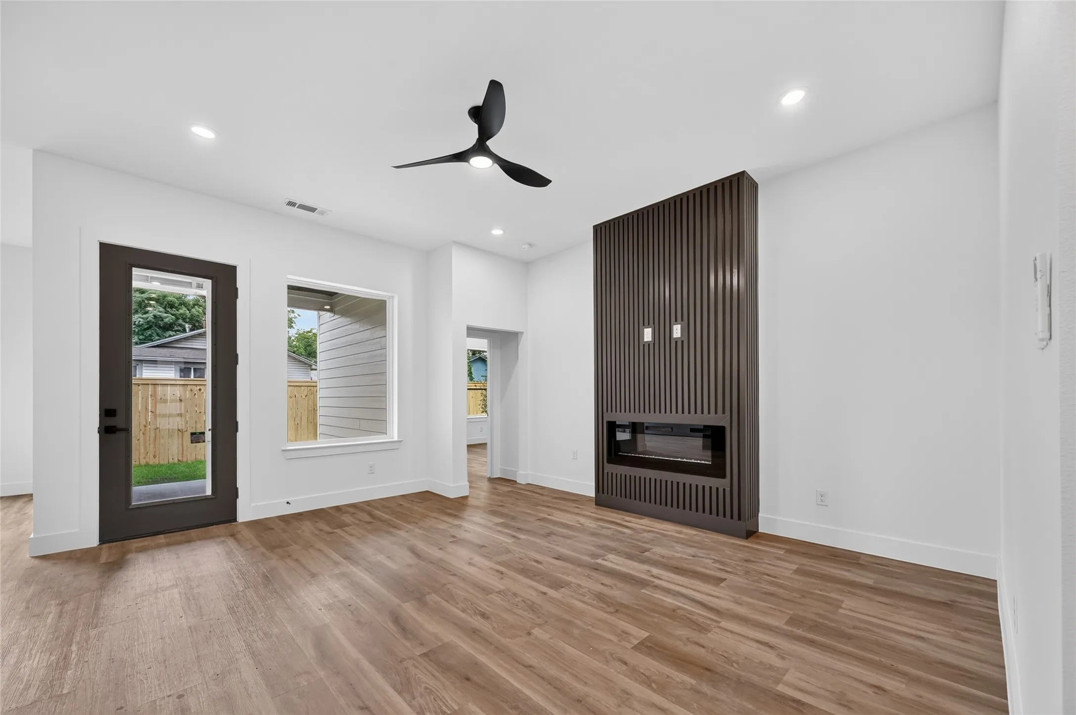 Spacious room featuring wood-finish flooring, a contemporary ceiling fan, and recessed lighting