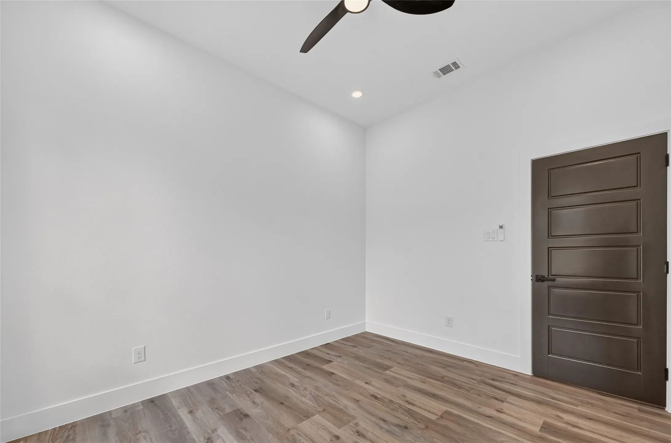 Interior room featuring wood-finish flooring, white walls, and white baseboards