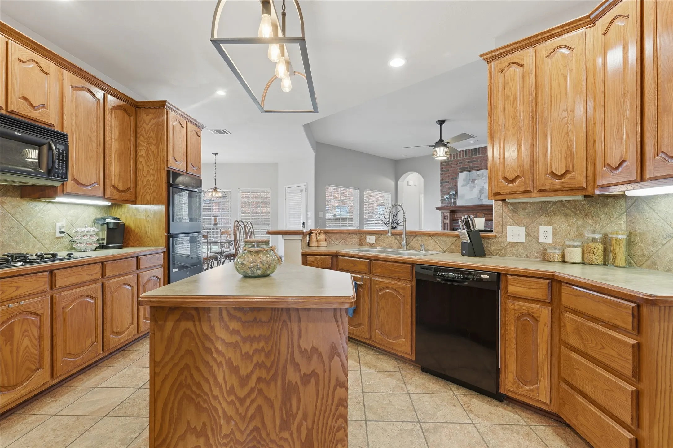 Kitchen featuring wood-finish cabinetry, a central island, integrated appliances, and a tile backsplash