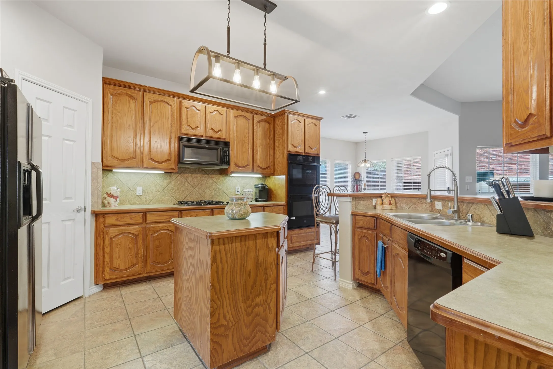Kitchen with wood cabinetry, a central island, tile flooring, and a built-in oven and microwave