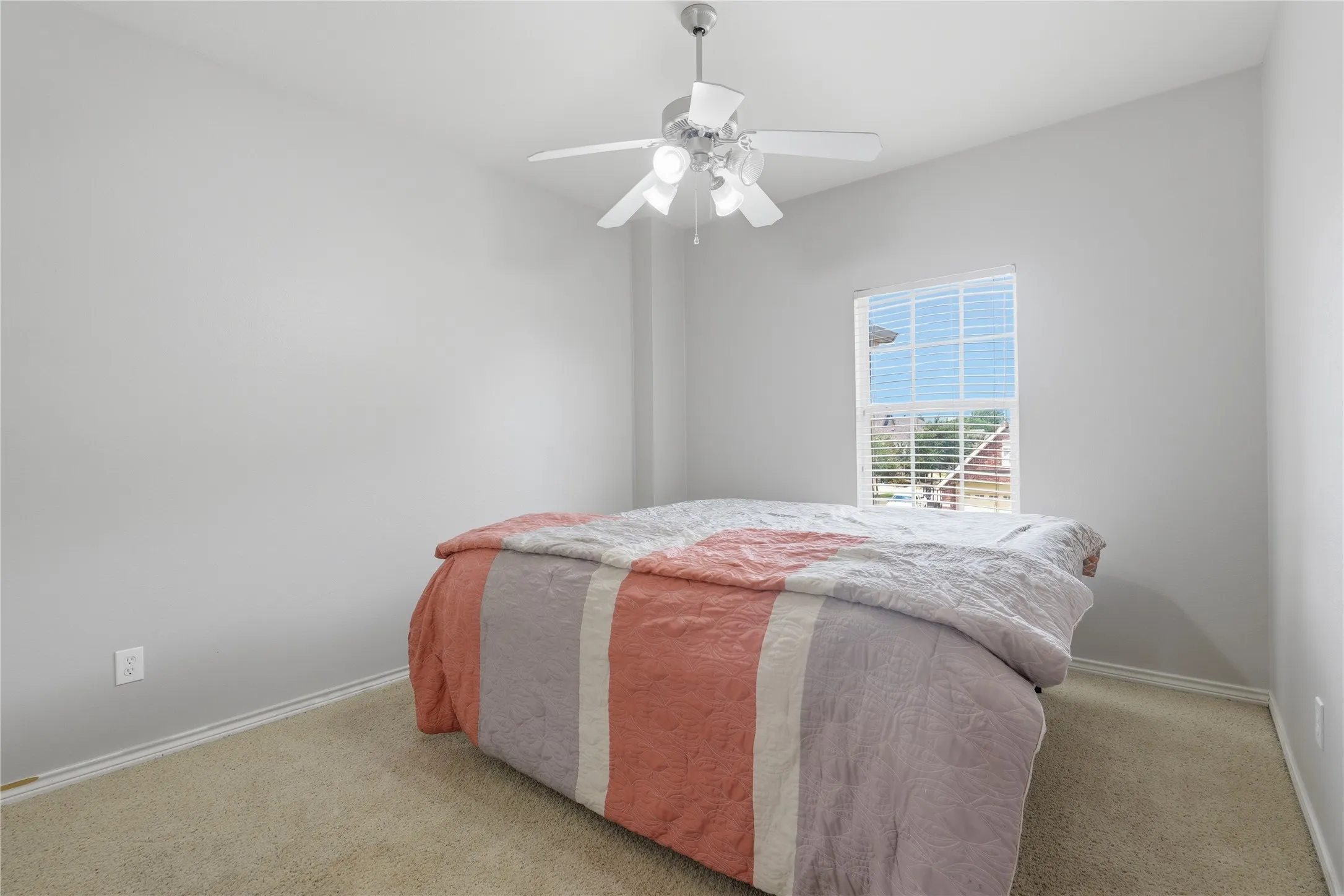 Carpeted bedroom featuring a ceiling fan with light fixture and a single window with blinds
