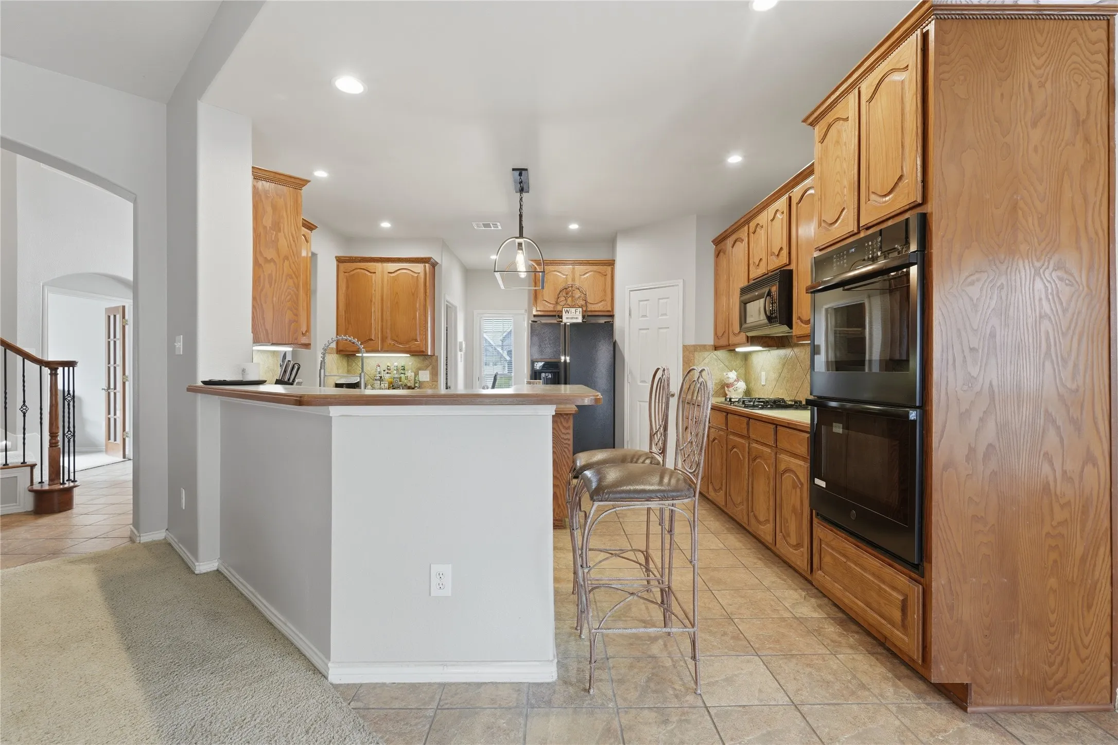 Kitchen featuring wood-finish cabinetry, integrated double ovens, and tile flooring