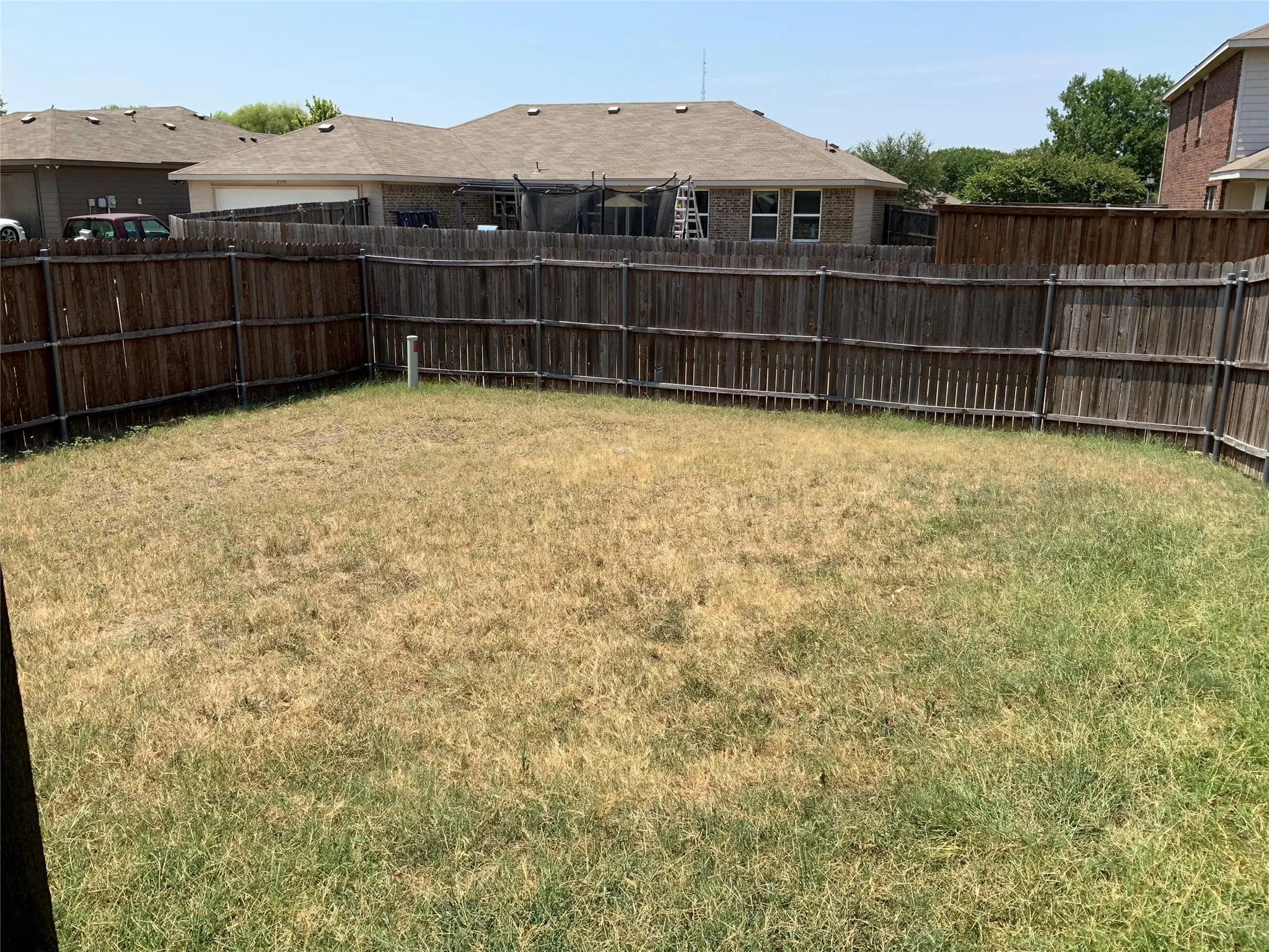 Expansive backyard featuring a full perimeter wood fence, providing definition to the outdoor space