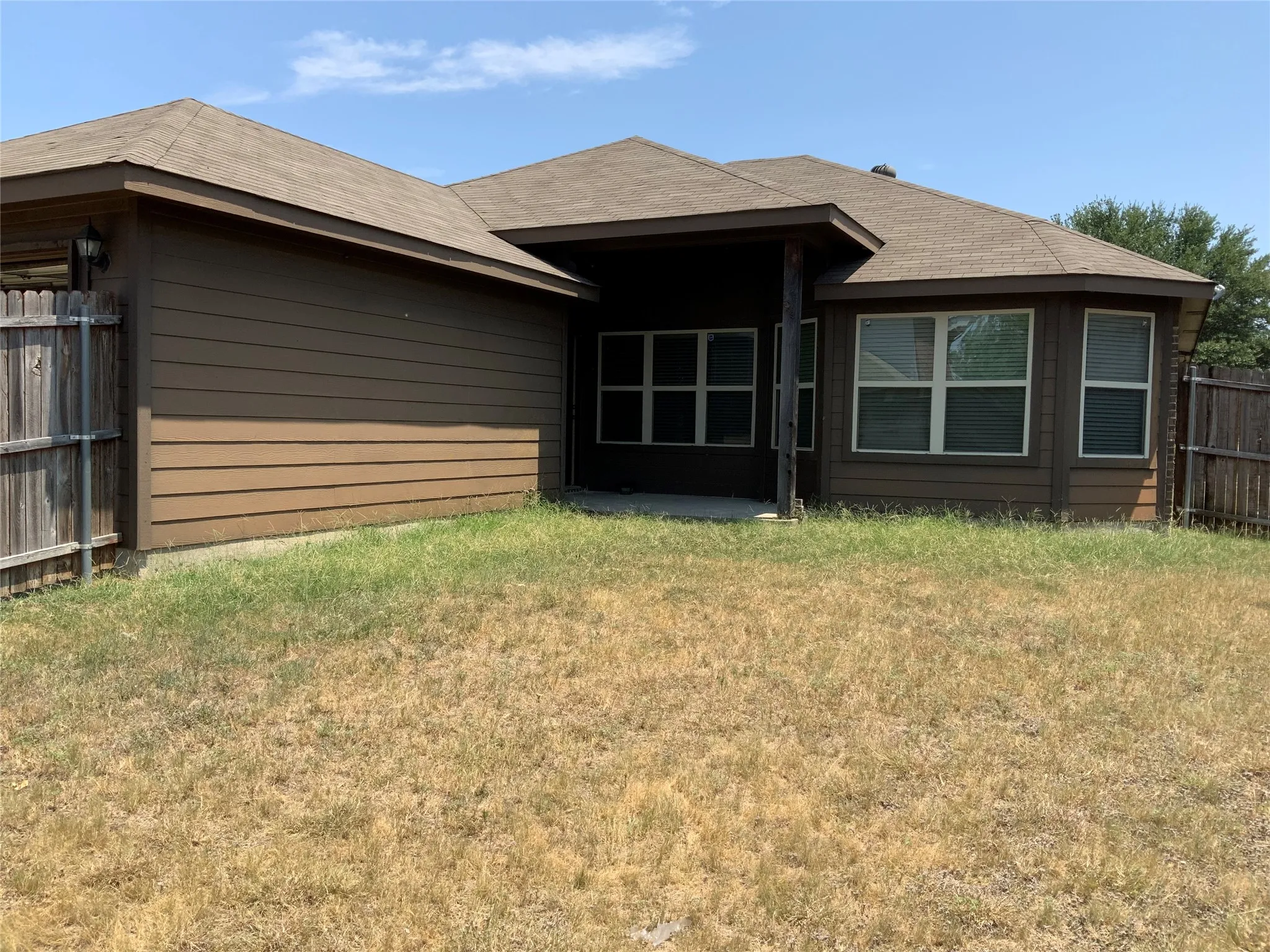 Rear exterior featuring a covered patio, multiple windows with blinds, and a durable shingle roof