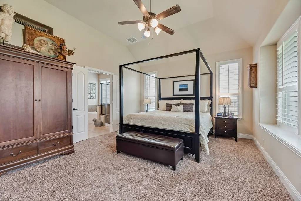 Partial View of Primary Bedroom - Measures Approximately 13'6'' X 17'6'' - Window Seat - 3.5 Inch Shutter Blinds, 5-inch Baseboards, Raised Ceiling, Ceiling Fan