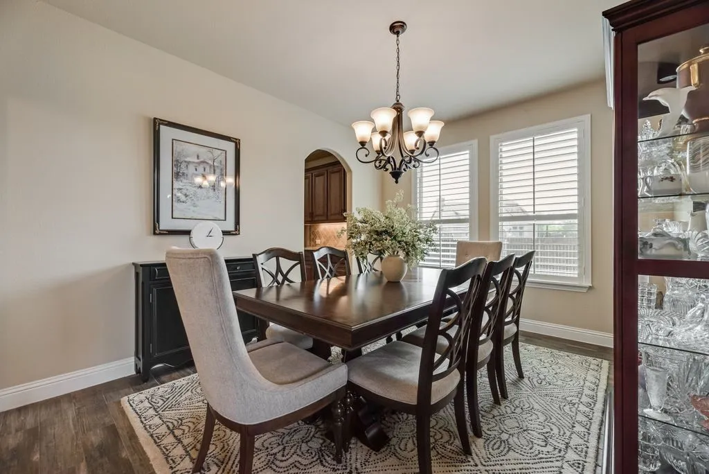 Dining Area Partial View 3 - View toward the 3.5-inch Shutter Blinds, and the Arch Opening to Kitchen. Decorative Chandelier and 5-inch Baseboards. Room Measures Approximately 11' x 13'7''