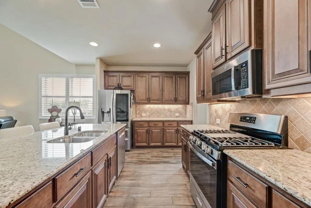 Kitchen Partial View - Upgraded GE Profile Gas Range with Griddle, GE Microwave, LG Thin Q Door in Door Refrigerator, Bosch Dishwasher. Door and Drawer Pulls added after build. Stainless Undermount Sink, Granite Counter Tops, Recessed Lighting.