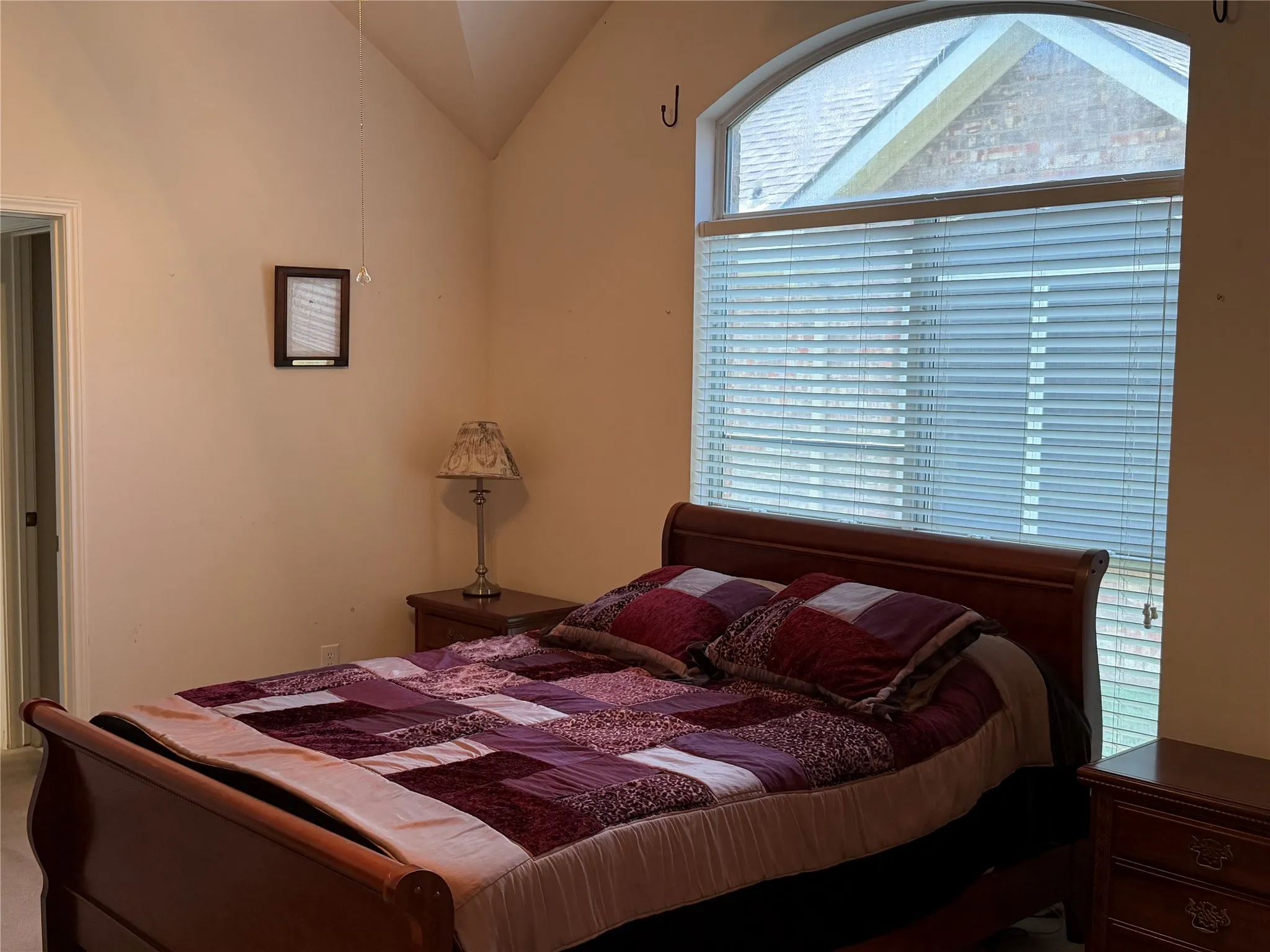 Room featuring a vaulted ceiling and an arched window with blinds
