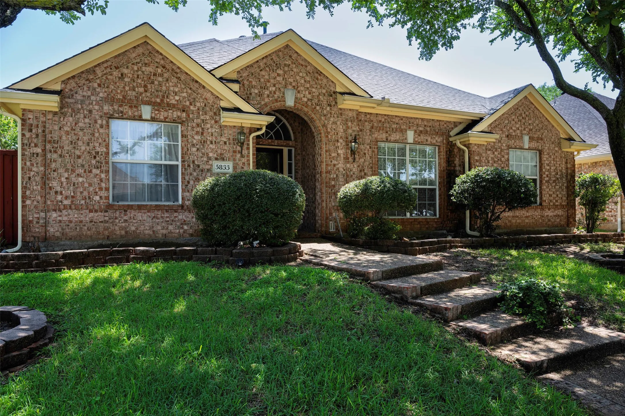 Brick exterior featuring a gabled roofline, arched entry, and stone-look steps