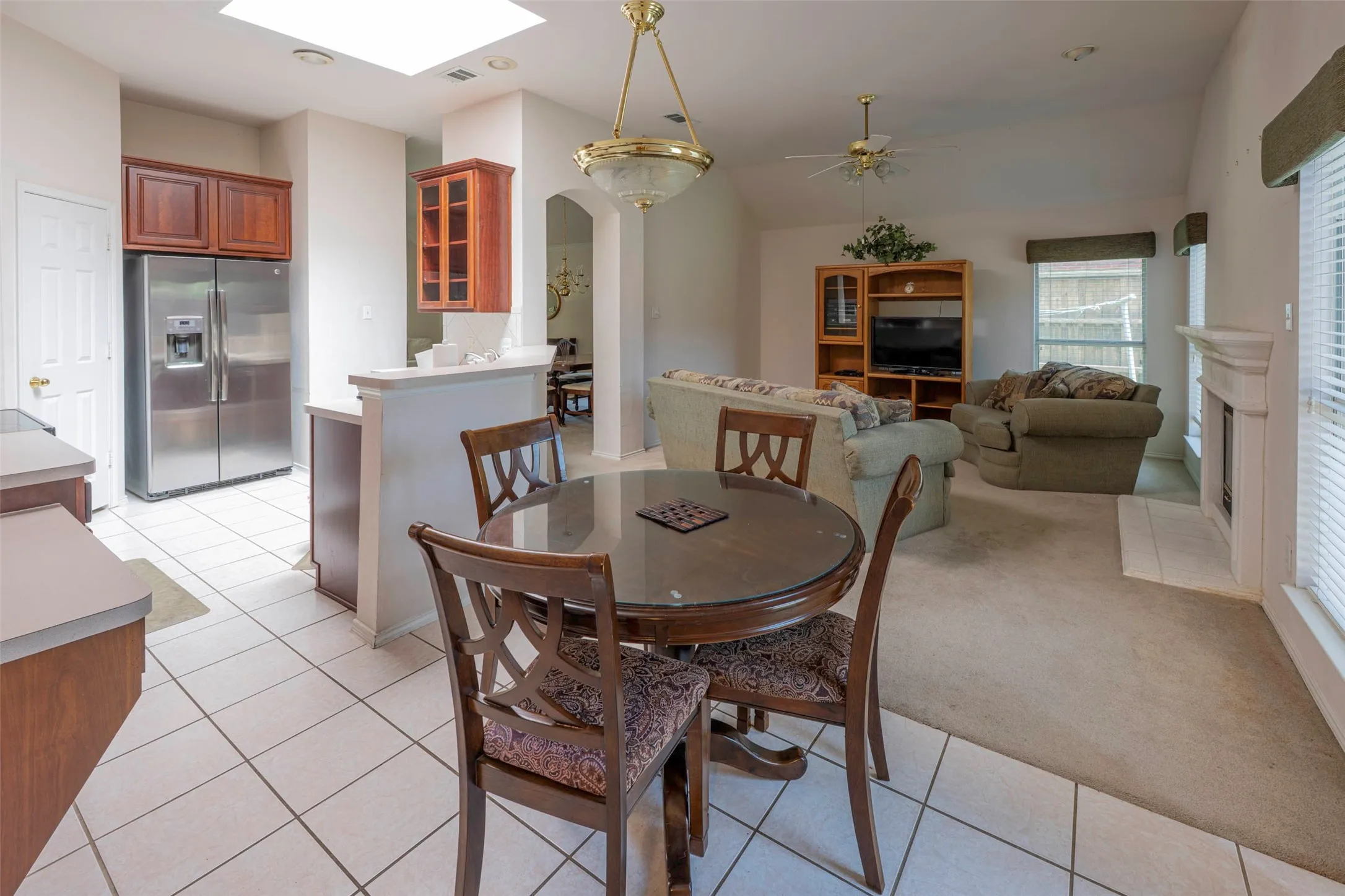 Tile flooring in the kitchen and breakfast dinging area with multiple windows, and a ceiling fan