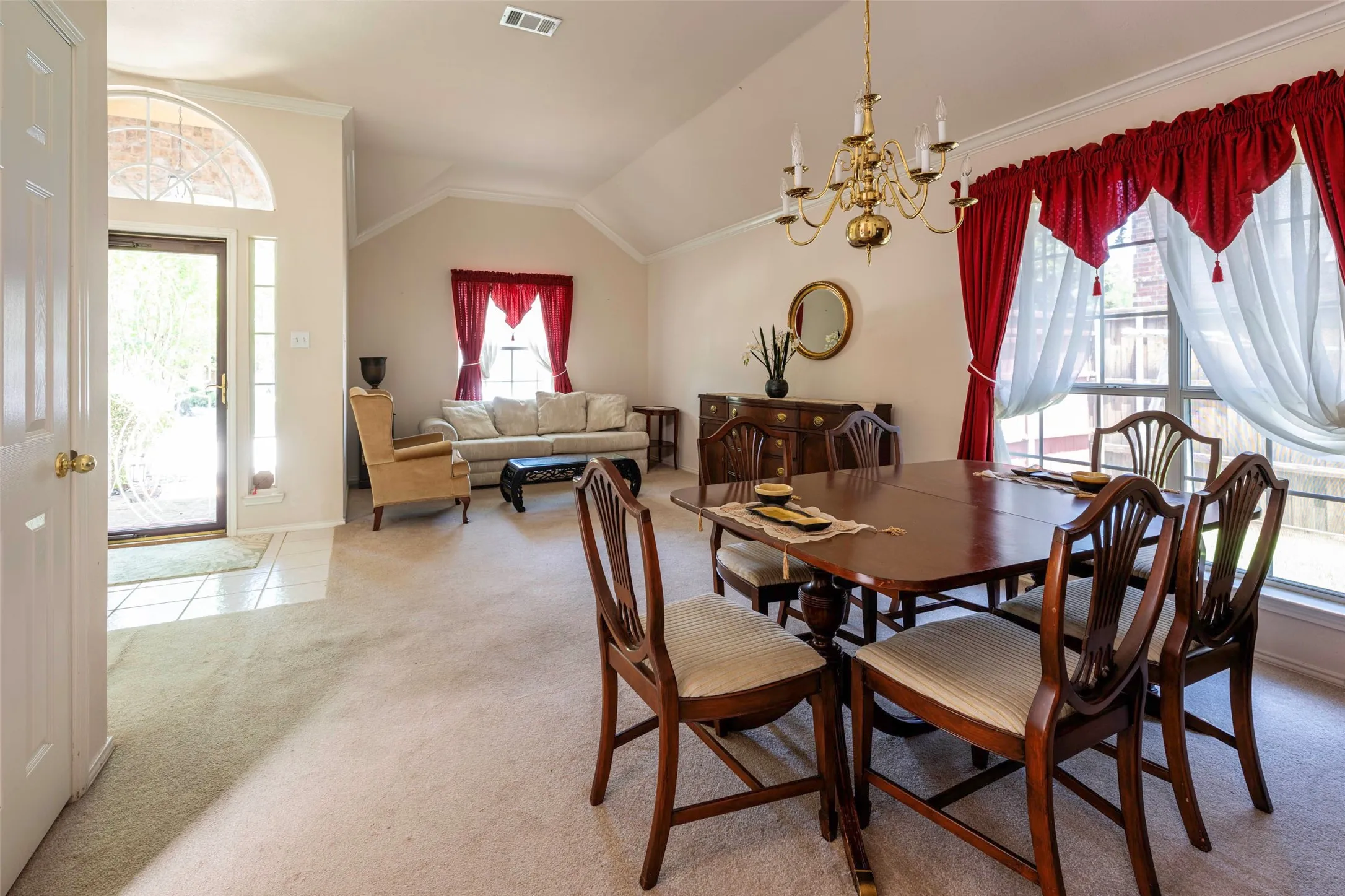 Carpeted dining area with large window, and vaulted ceilings