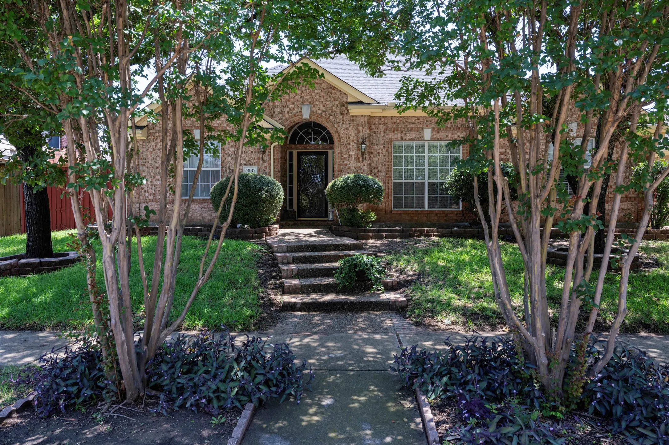 Brick exterior home featuring an arched entryway, decorative front door